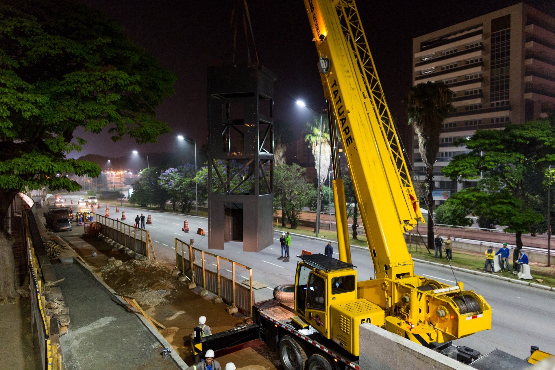 Um grande guindaste amarelo está trabalhando em um canteiro de obras à noite