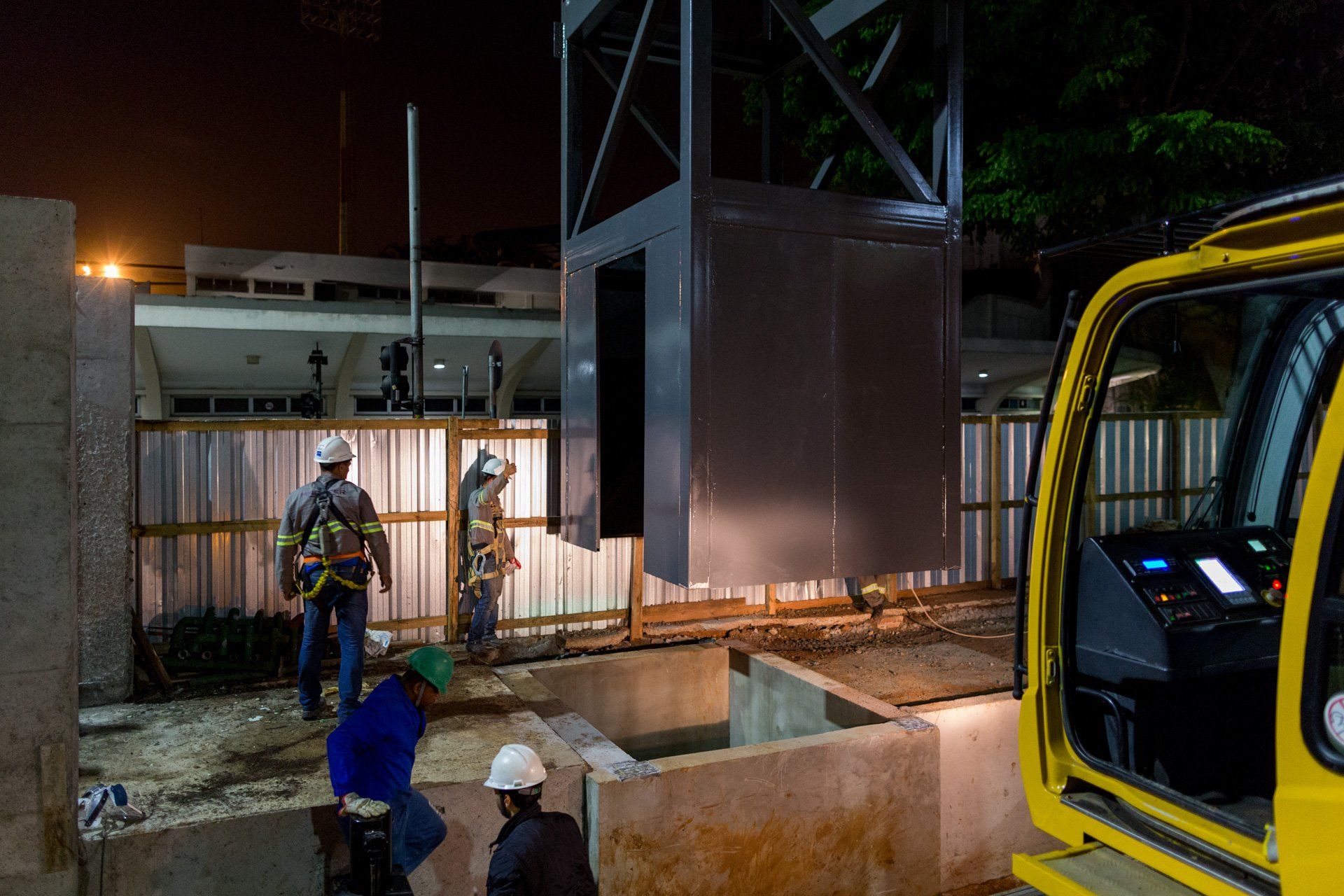Um grupo de trabalhadores da construção civil está trabalhando em um prédio à noite.