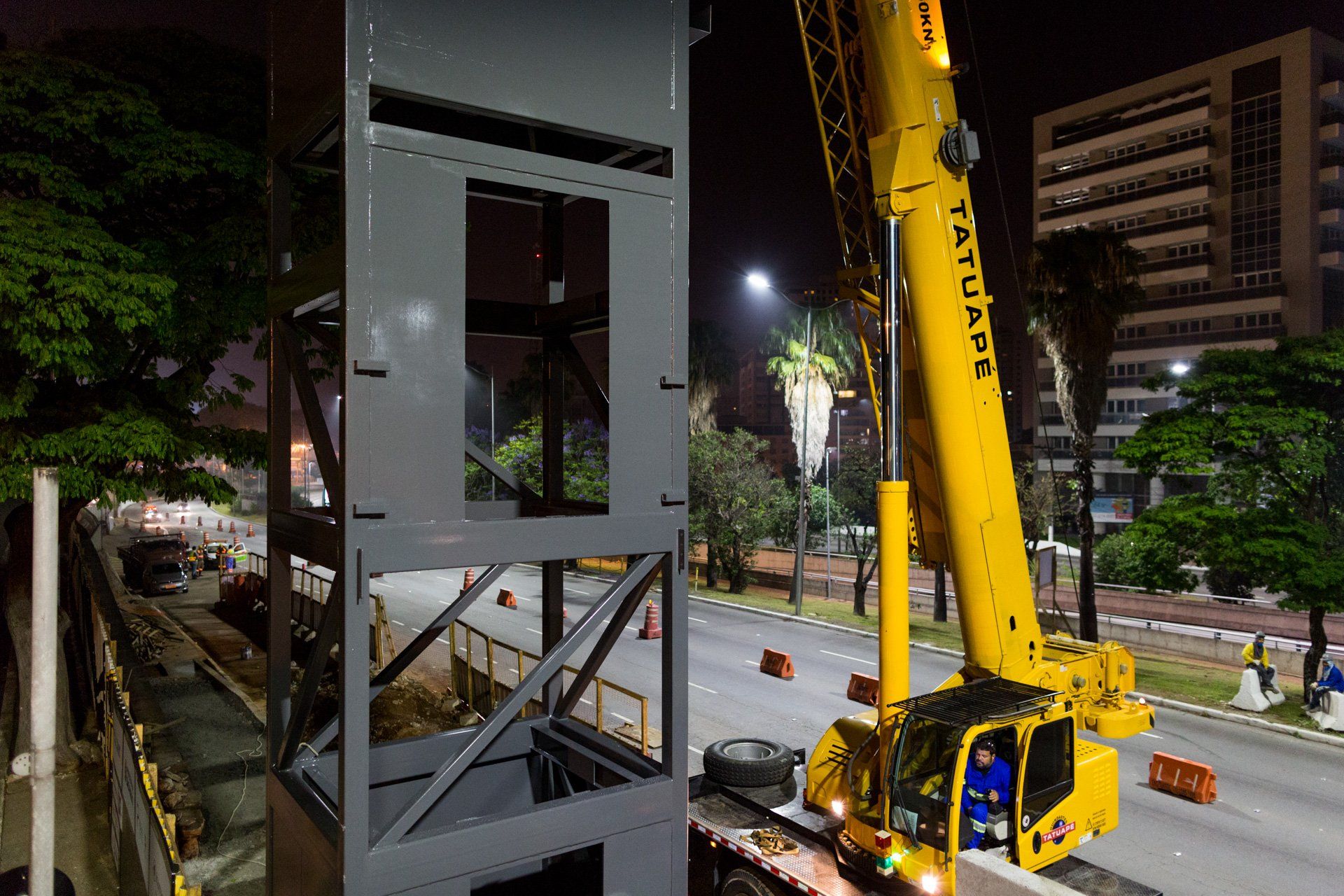 Um grande guindaste amarelo está trabalhando em um prédio à noite.