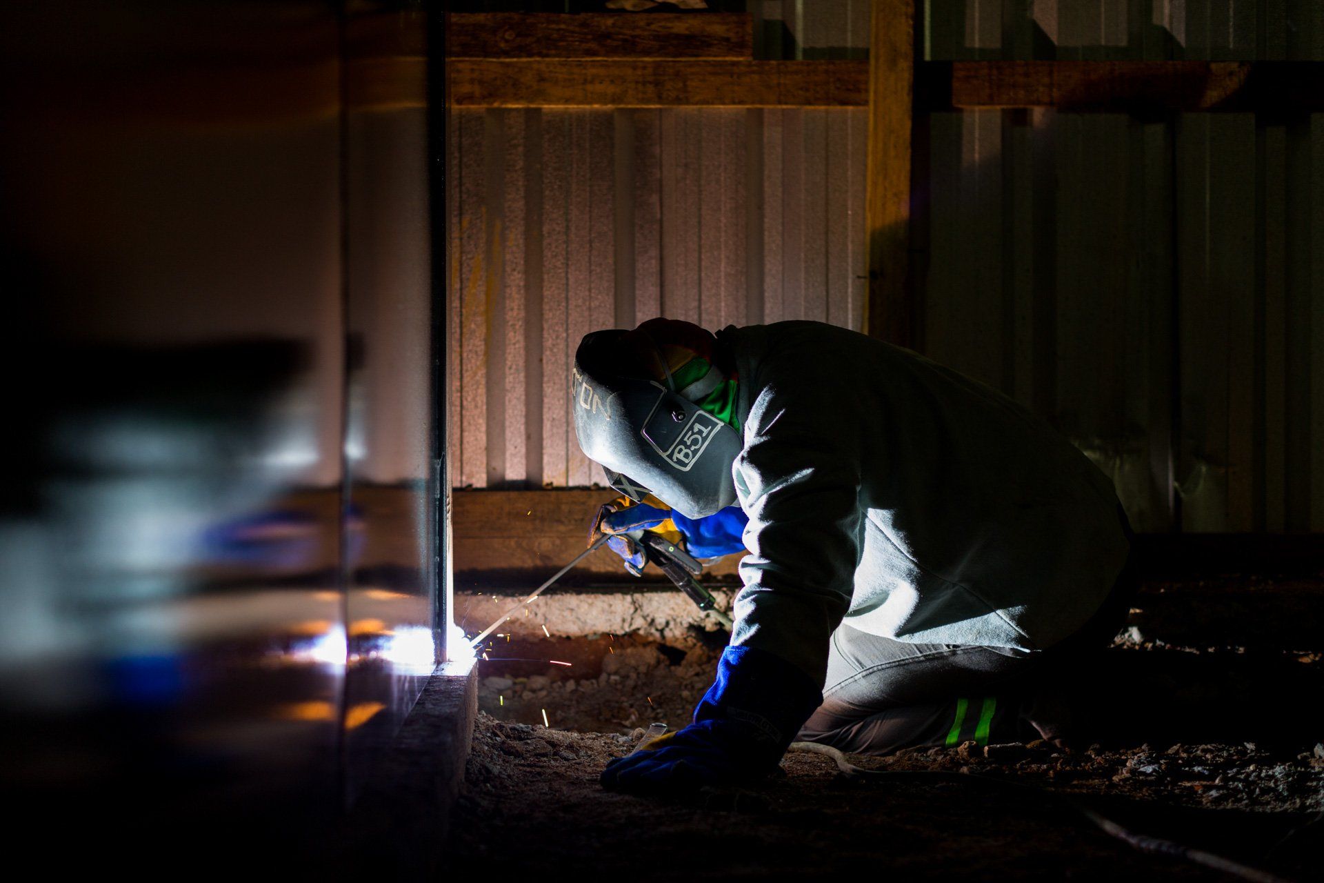 Um homem está soldando um pedaço de metal no escuro.