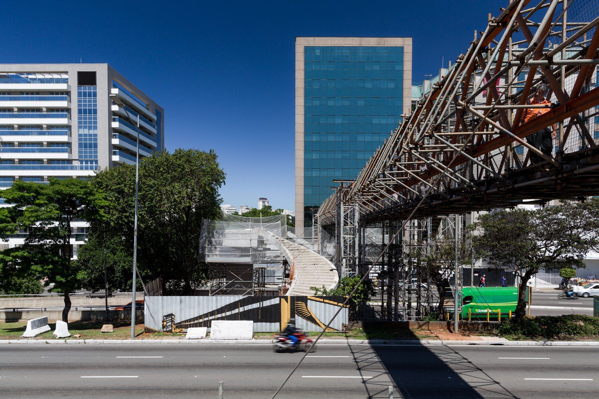 Uma pessoa está andando de moto em uma rua em frente a um prédio em construção