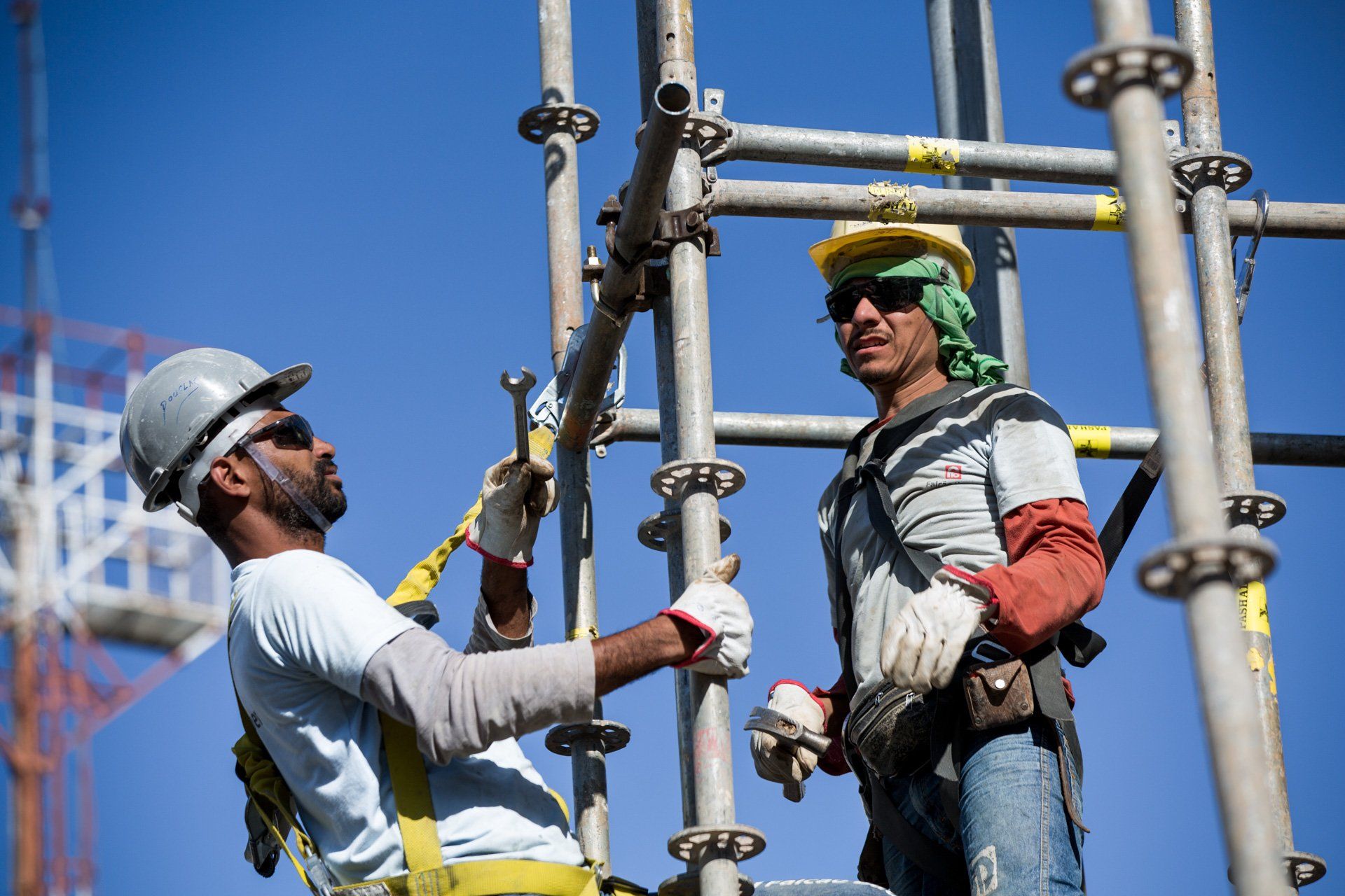 Dois trabalhadores da construção civil estão trabalhando em um andaime em um canteiro de obras.