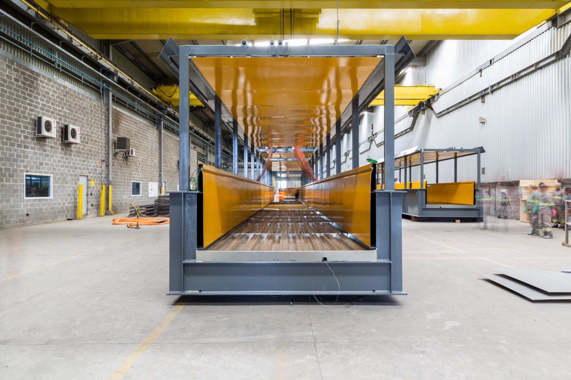 Uma grande estrutura metálica está sendo construída em uma fábrica.