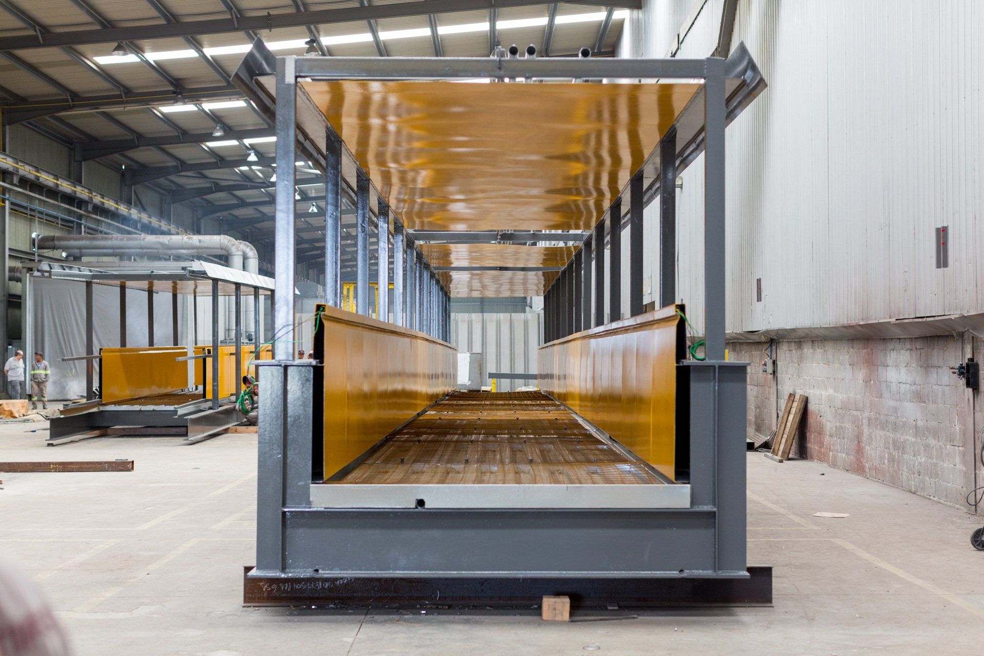 Uma grande estrutura metálica está sendo construída em uma fábrica.