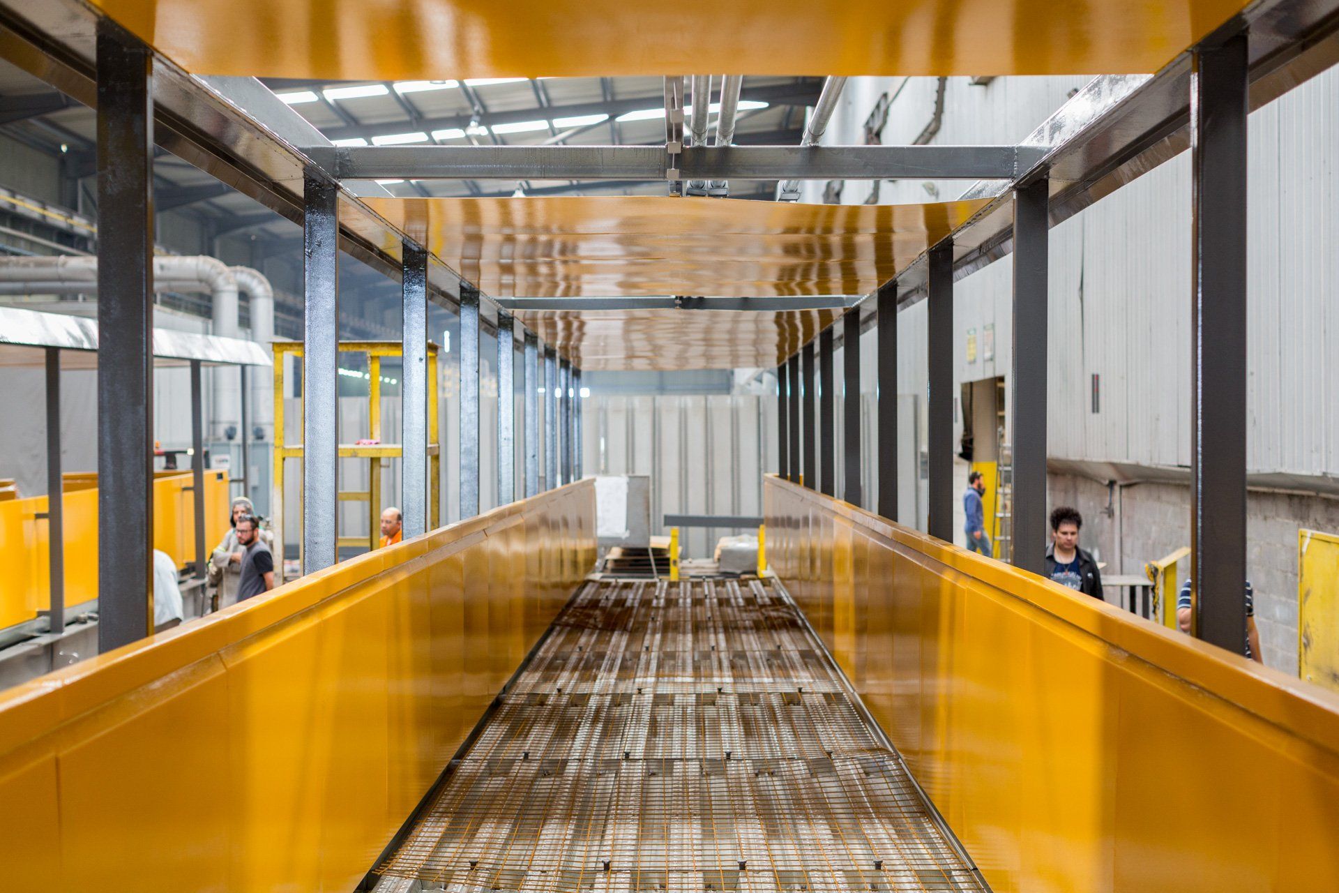 Um homem está parado no meio de um longo corredor de uma fábrica.