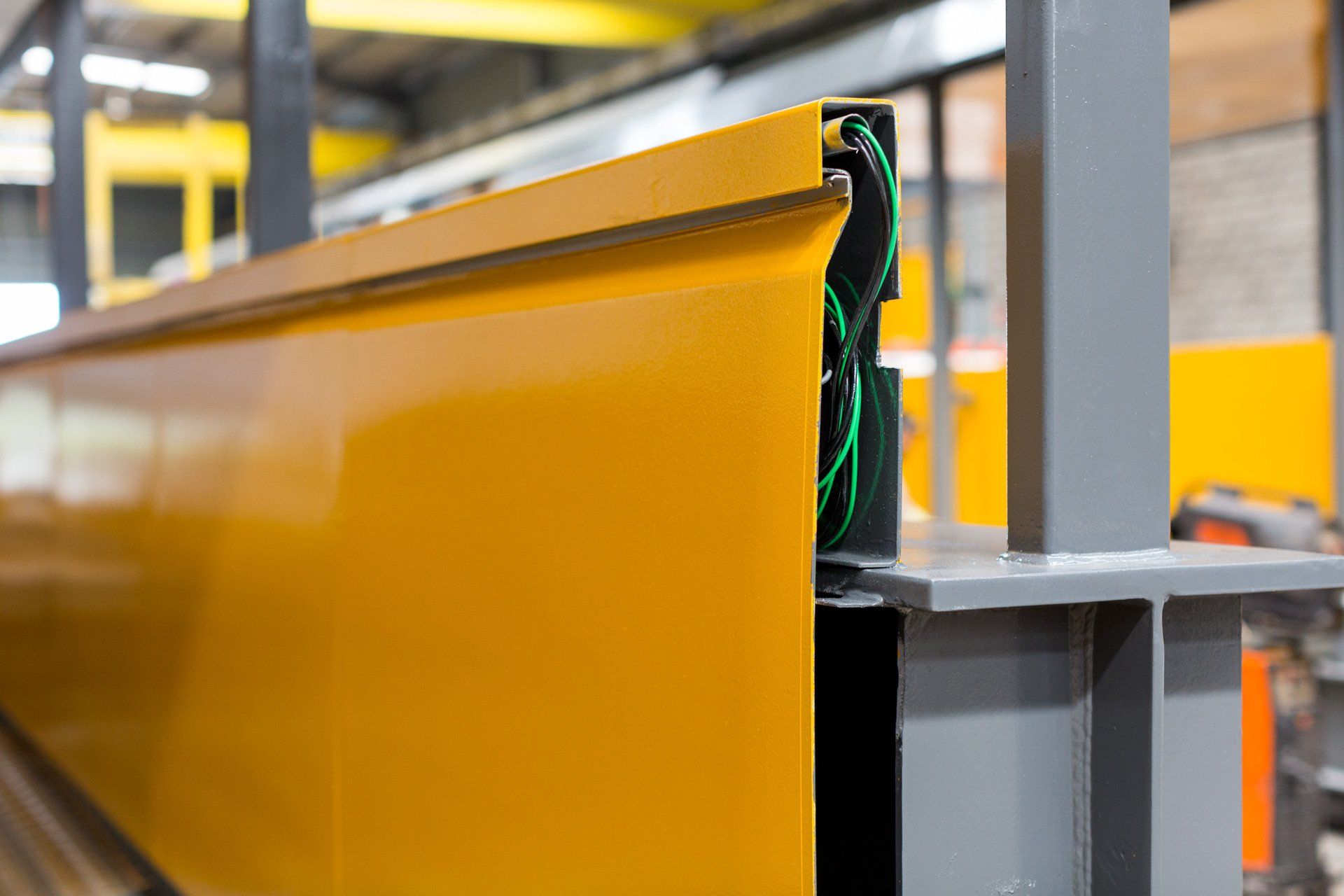 Um close de uma viga de metal amarela em uma fábrica.