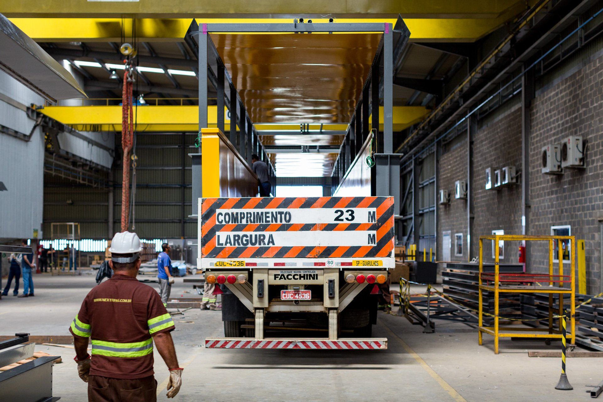 Um homem está parado na frente de um caminhão que tem o número 23 na traseira