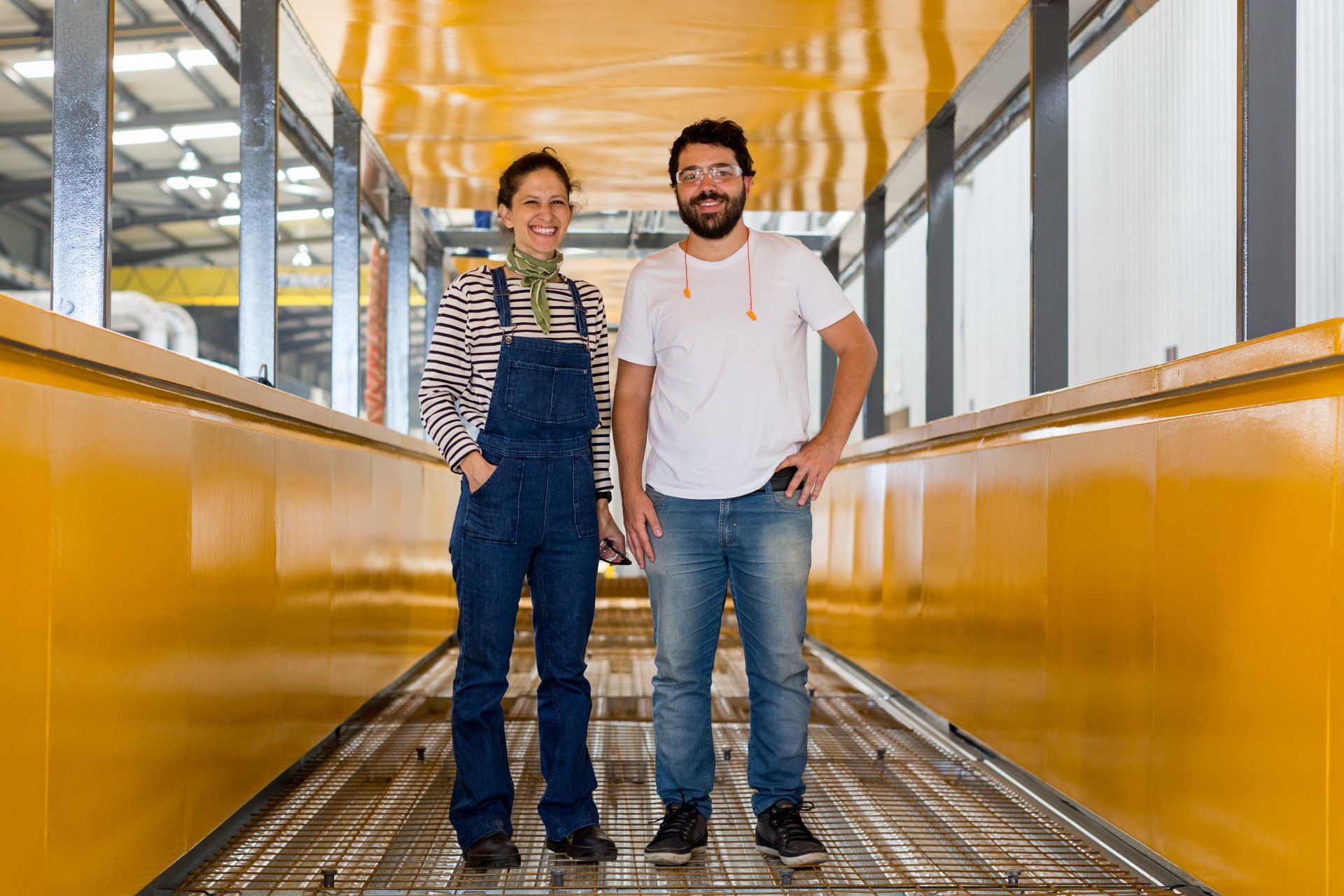 Um homem e uma mulher estão lado a lado em uma fábrica.