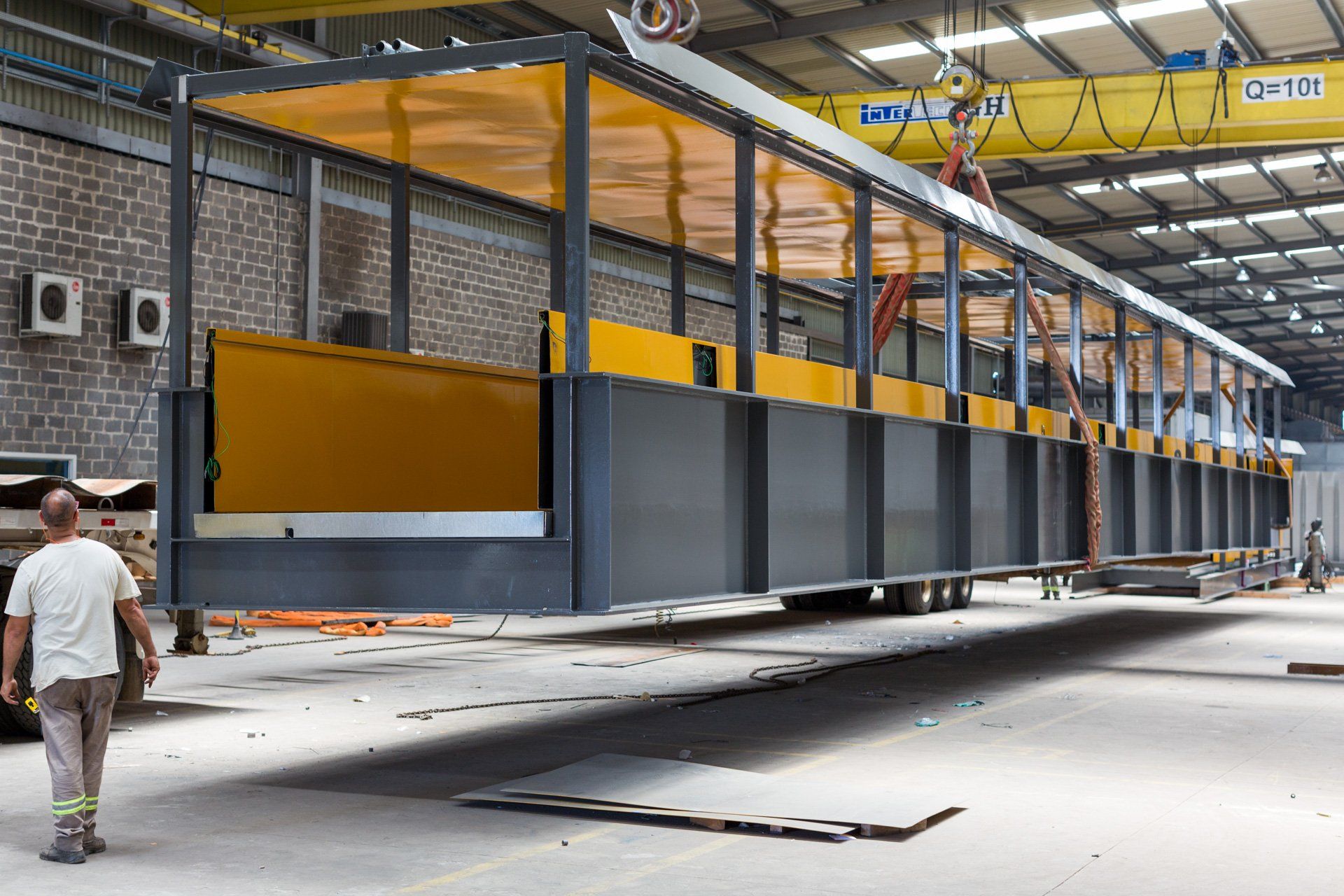 Um homem caminha em frente a uma grande estrutura metálica em um armazém.