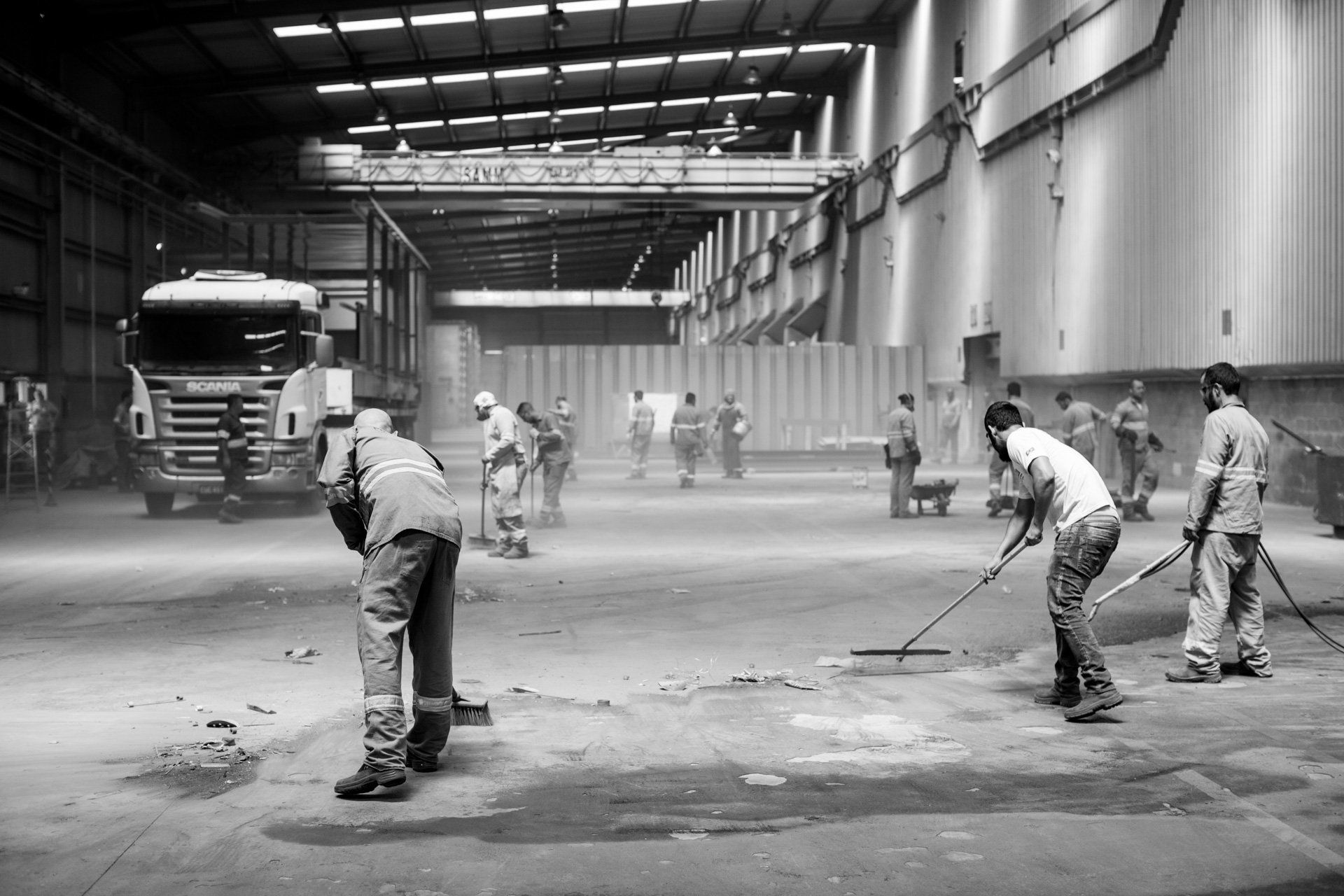 Um grupo de homens está limpando o chão de um armazém.