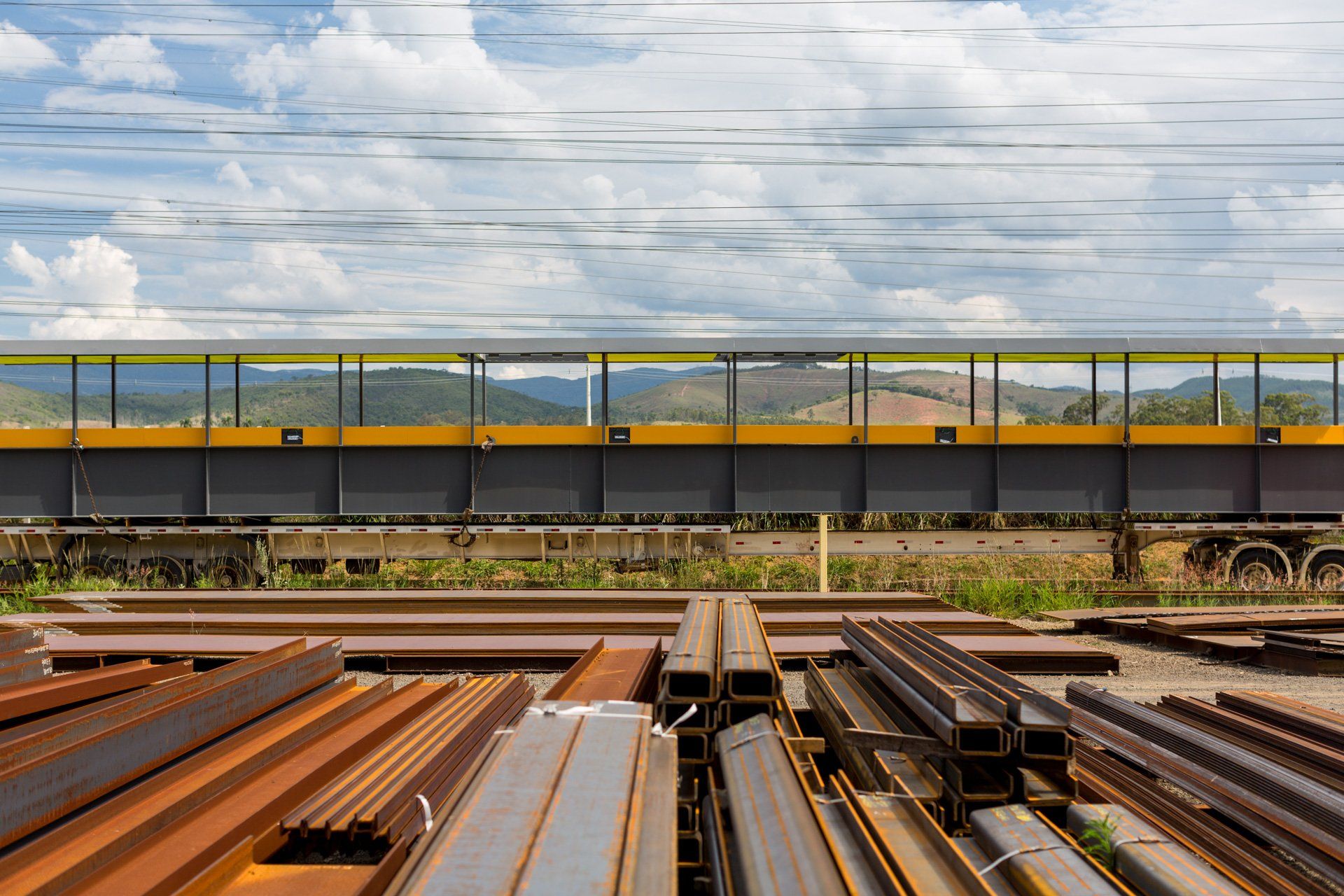 Um trem passa por uma ponte próximo a uma pilha de metal.