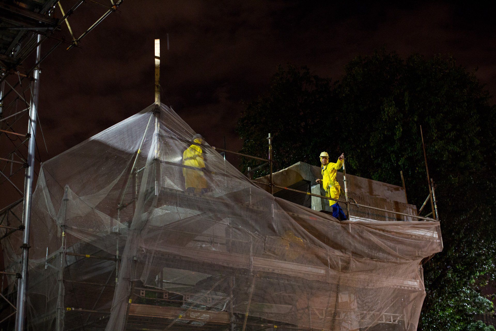 Um grupo de trabalhadores da construção civil está trabalhando em um prédio à noite.