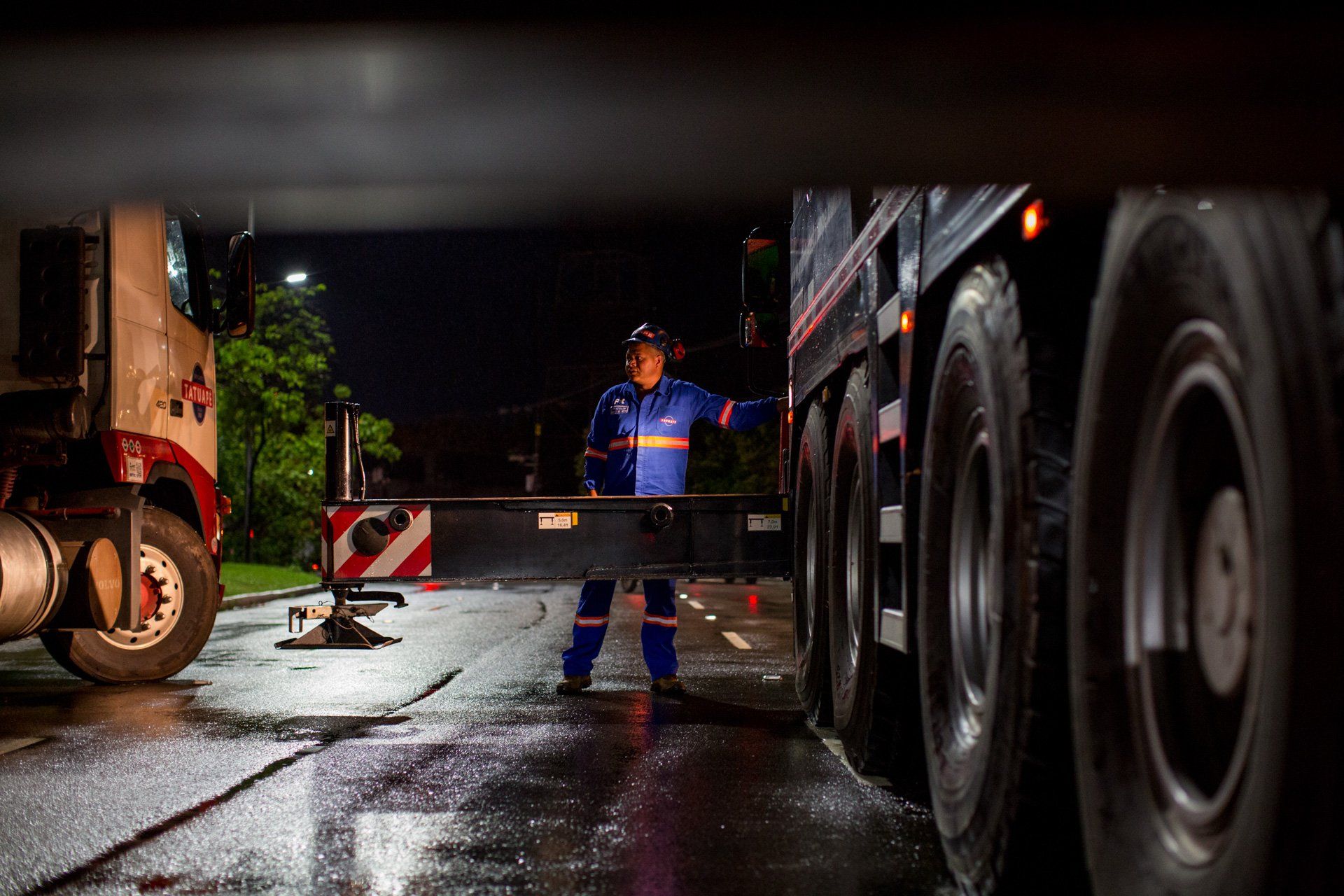 Um homem está parado na frente de um grande caminhão à noite.