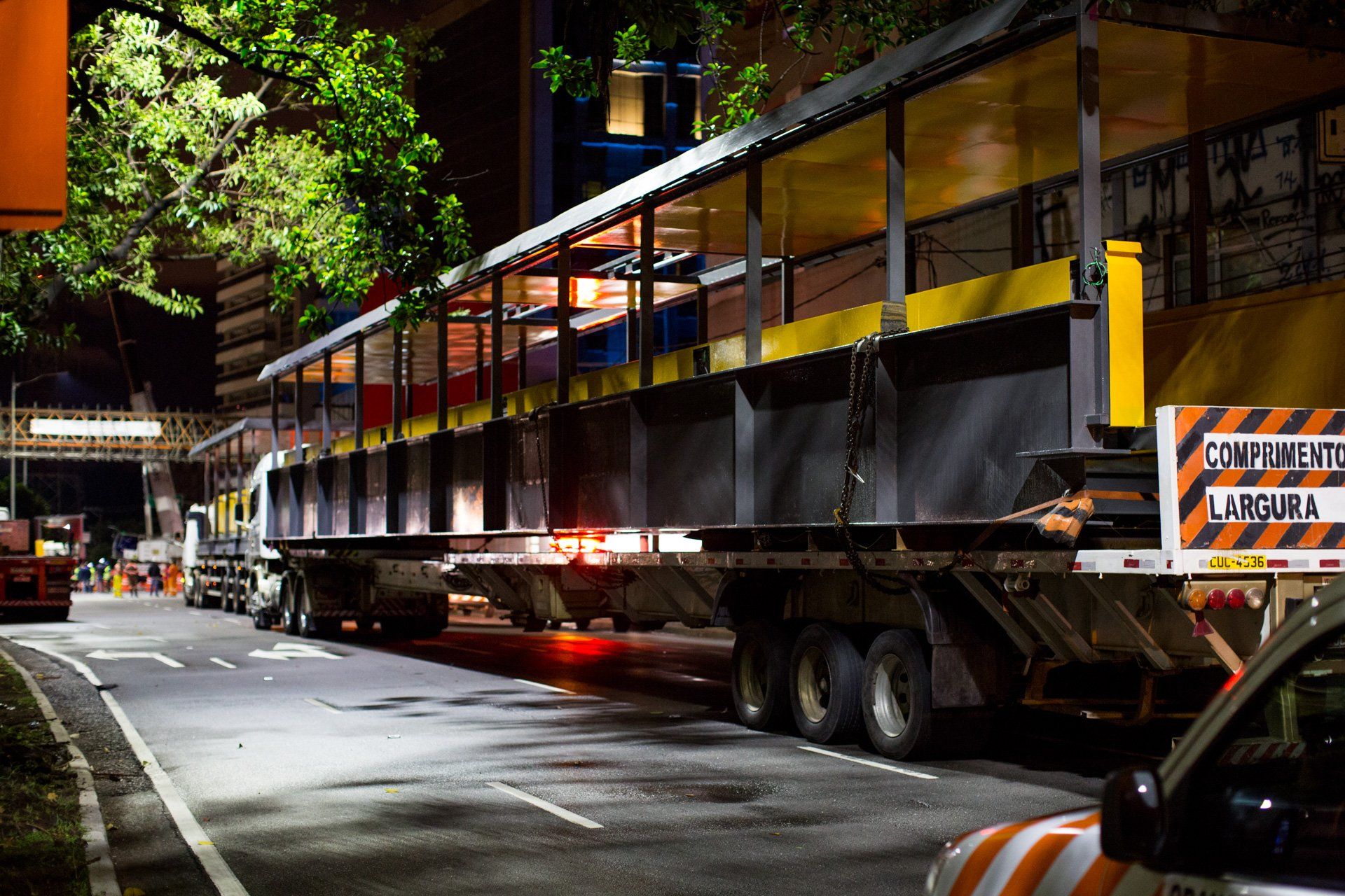 Um grande caminhão está passando por uma rua à noite