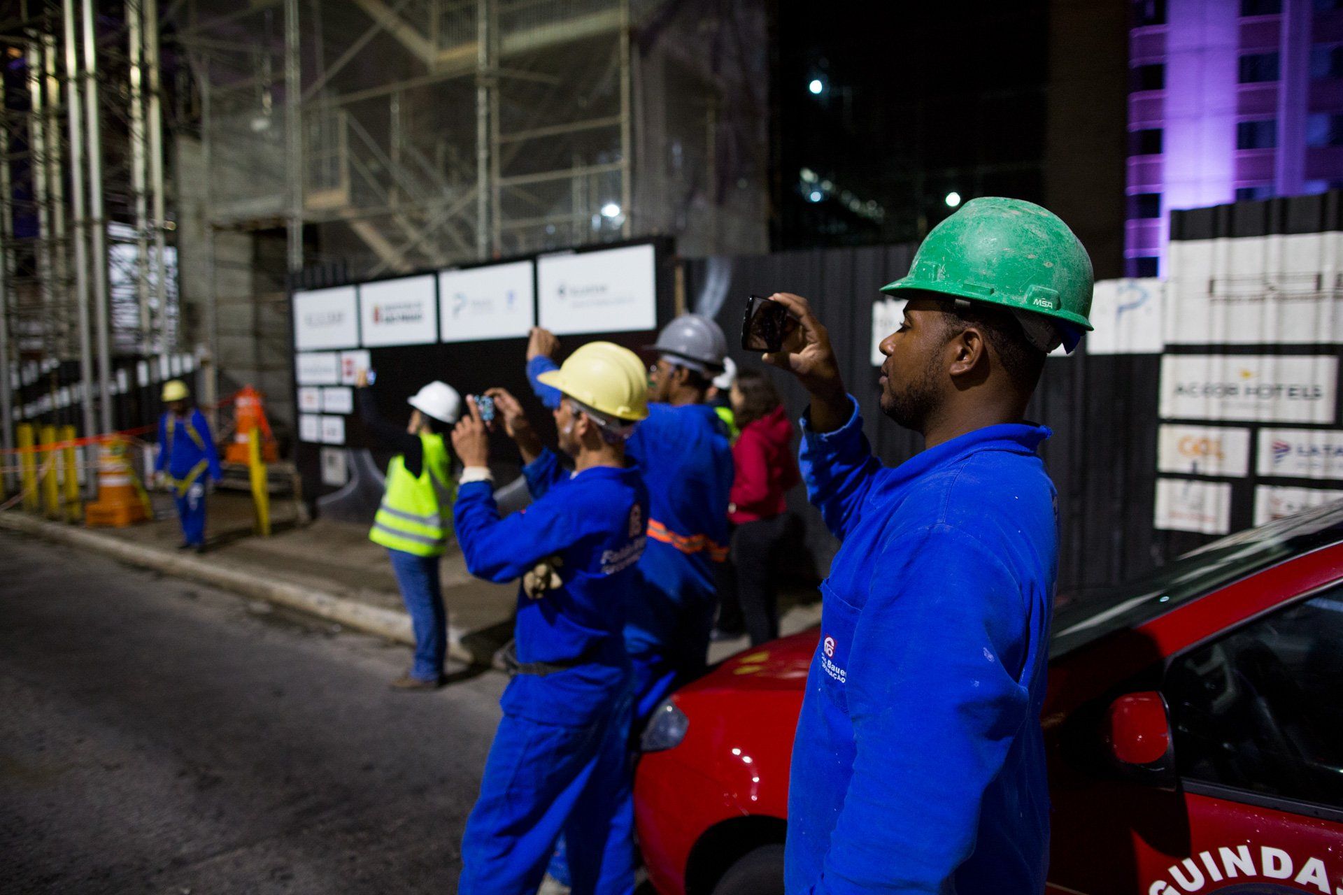 Um grupo de trabalhadores da construção civil está tirando fotos de um prédio em construção.