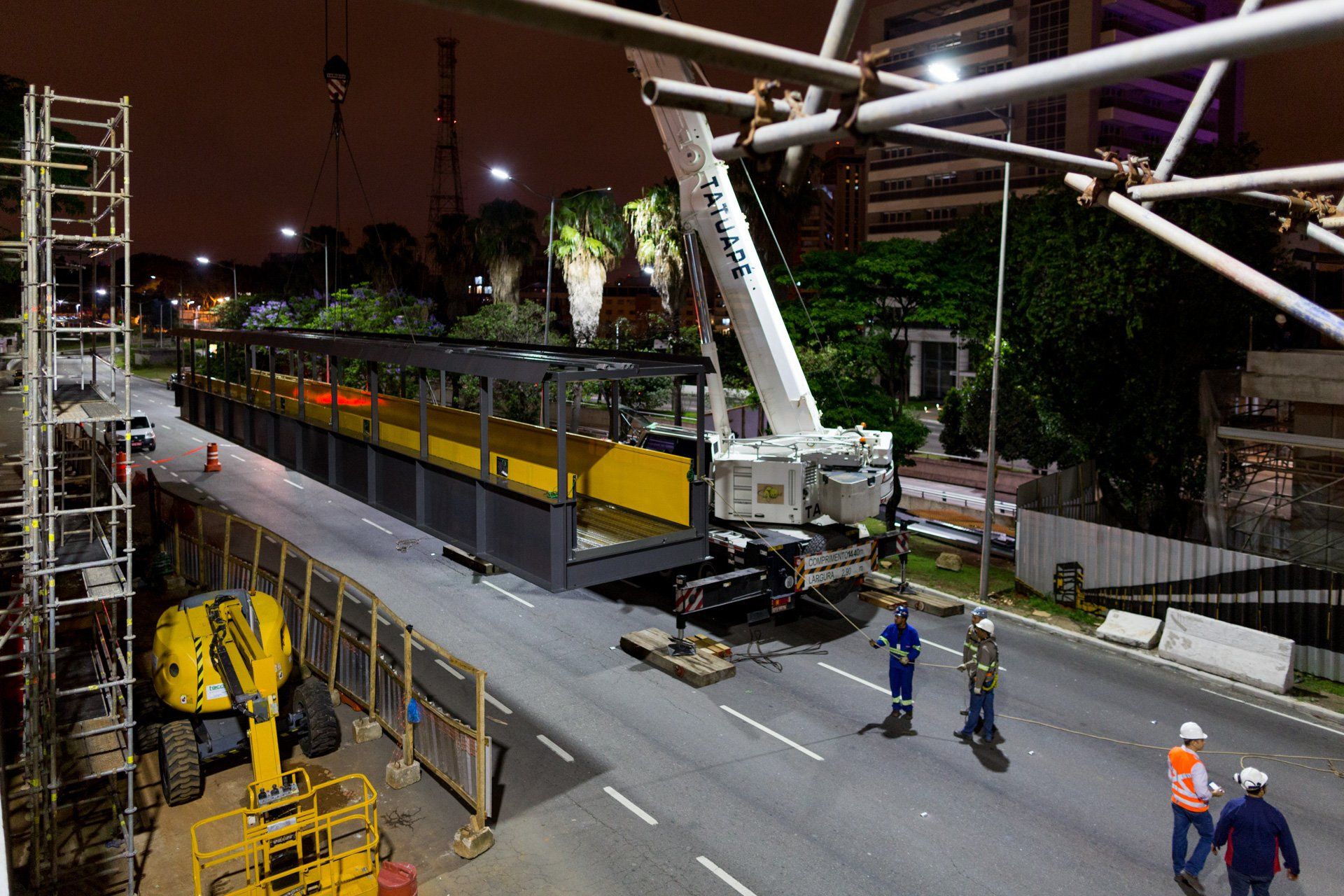 Um canteiro de obras à noite com um grande guindaste na beira da estrada.