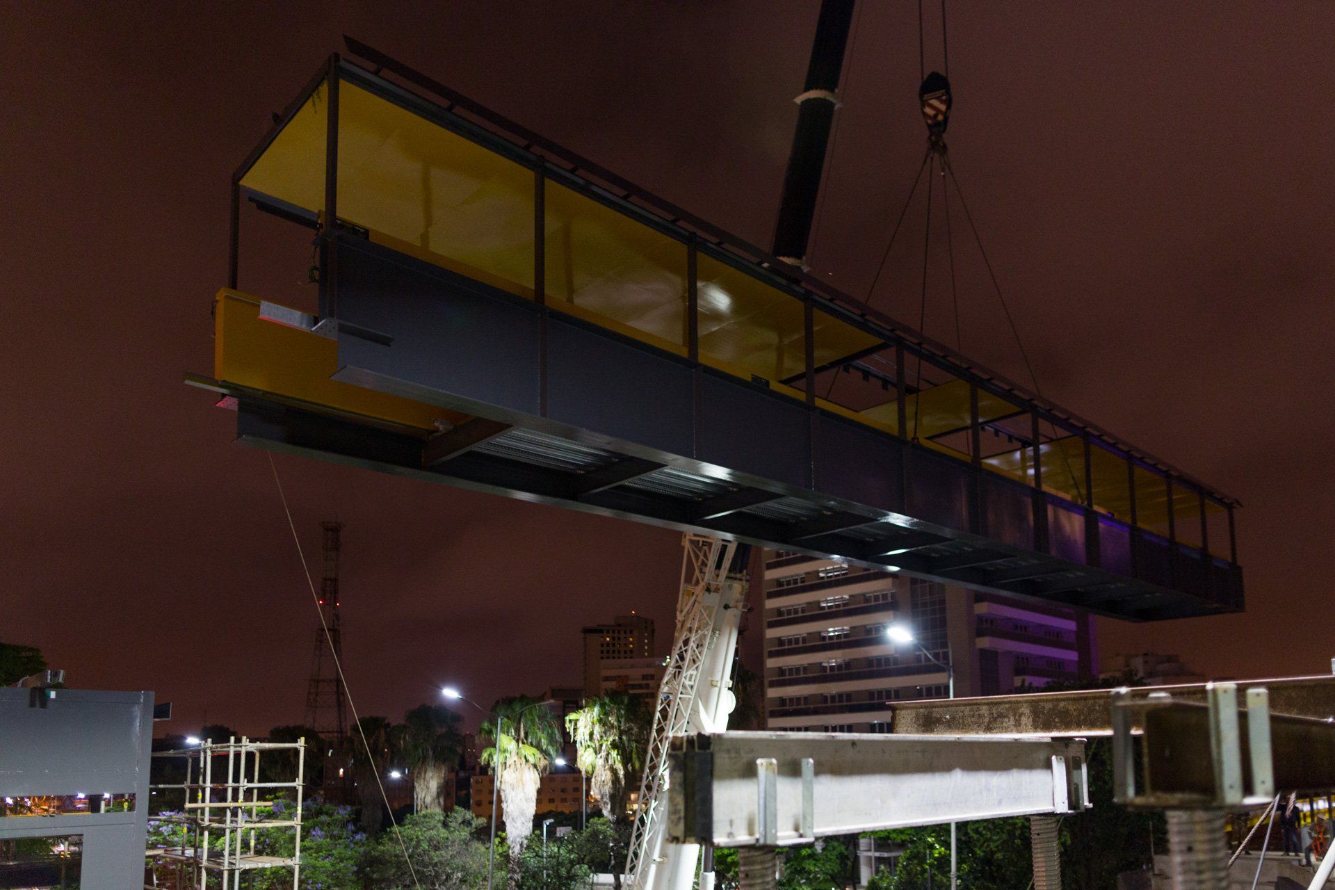 Uma ponte está sendo levantada por um guindaste à noite.