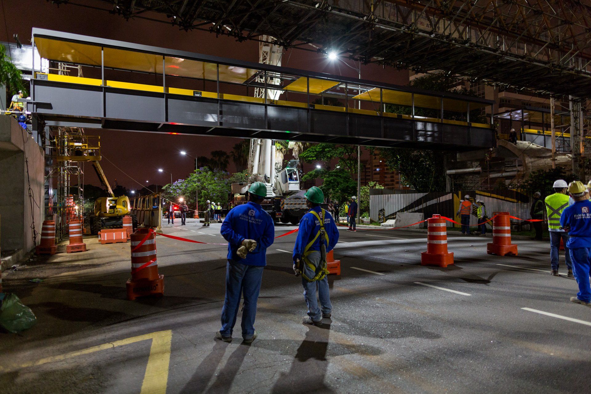 Um grupo de trabalhadores da construção civil está parado na rua à noite.