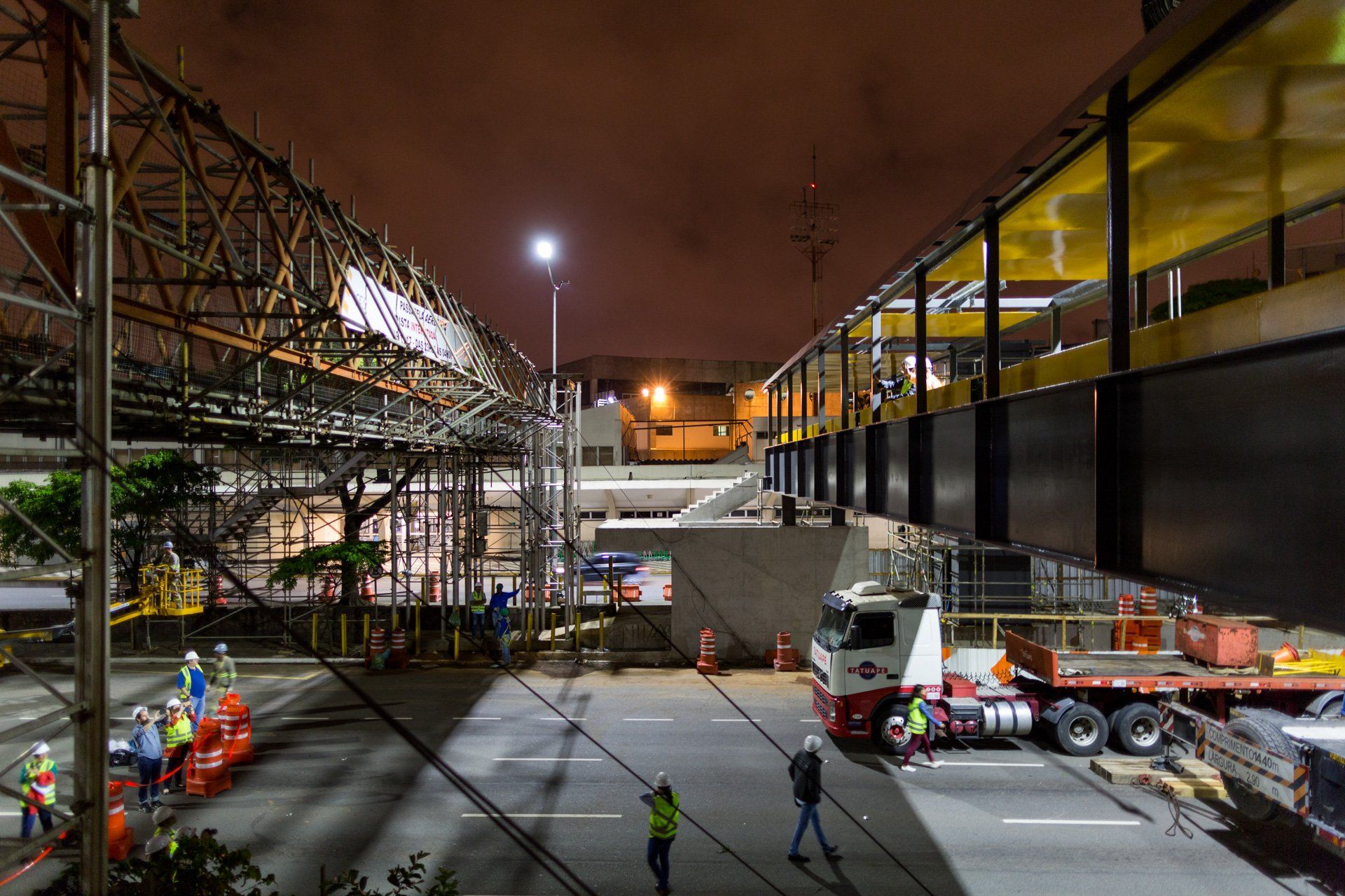 Um canteiro de obras à noite com muitos caminhões e pessoas