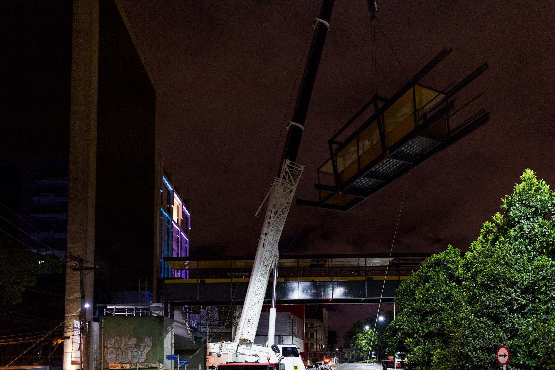 Um grande guindaste está levantando um prédio à noite