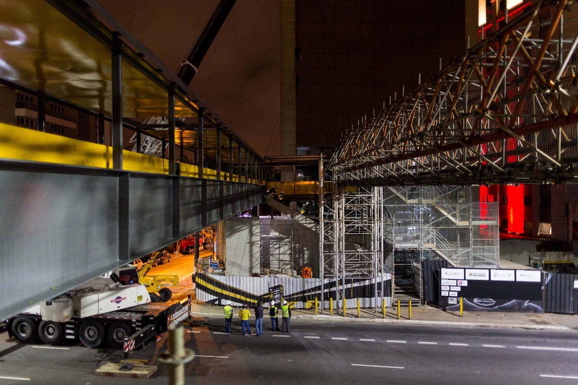 Um caminhão está estacionado na beira da estrada em frente a um canteiro de obras à noite.