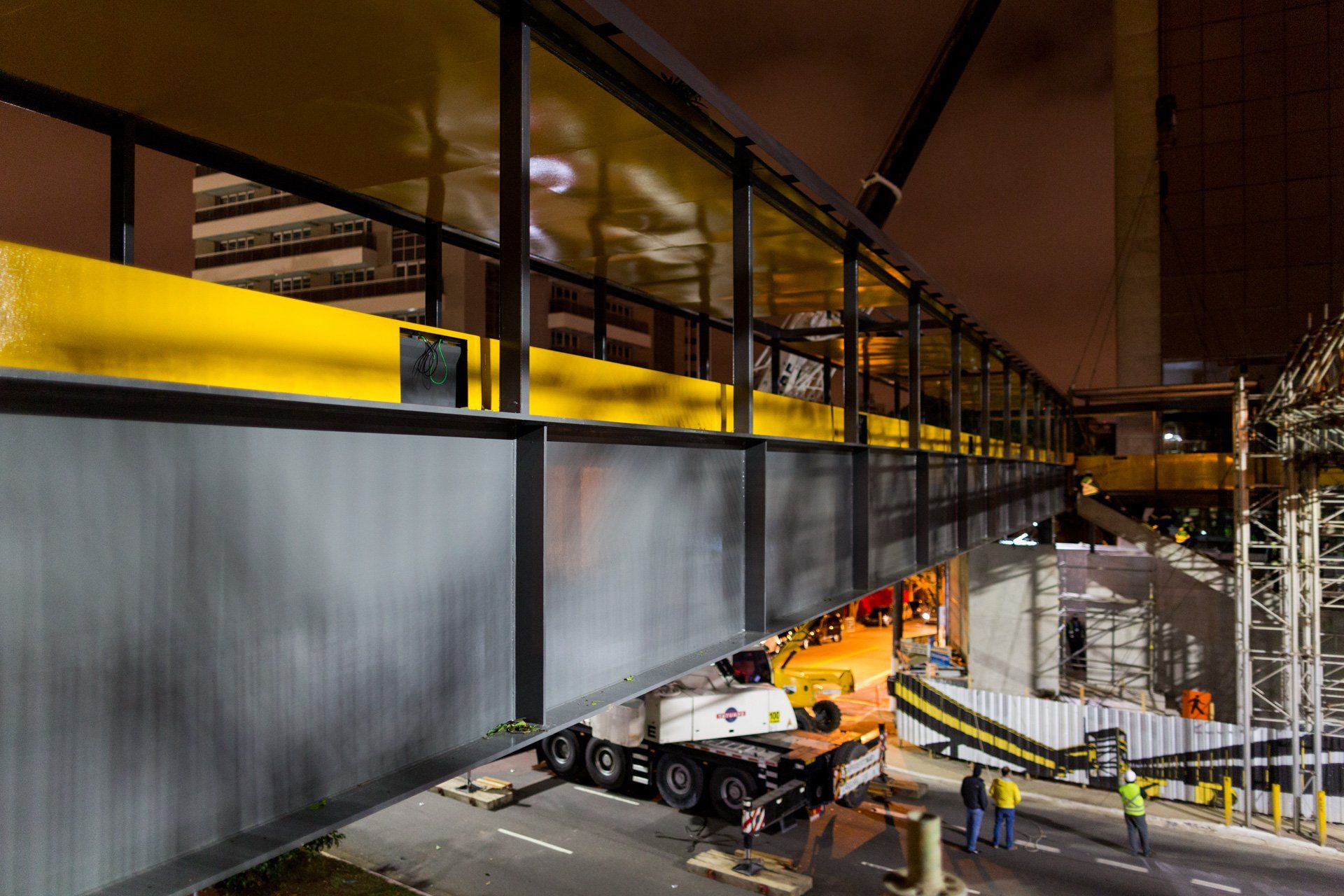 Um caminhão está passando por baixo de uma ponte à noite.