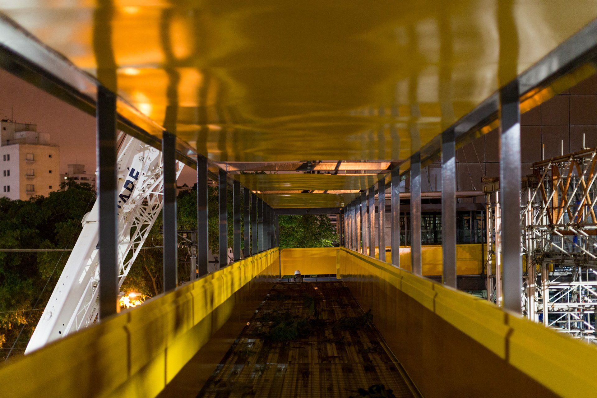 Uma ponte amarela com uma montanha russa ao fundo à noite.