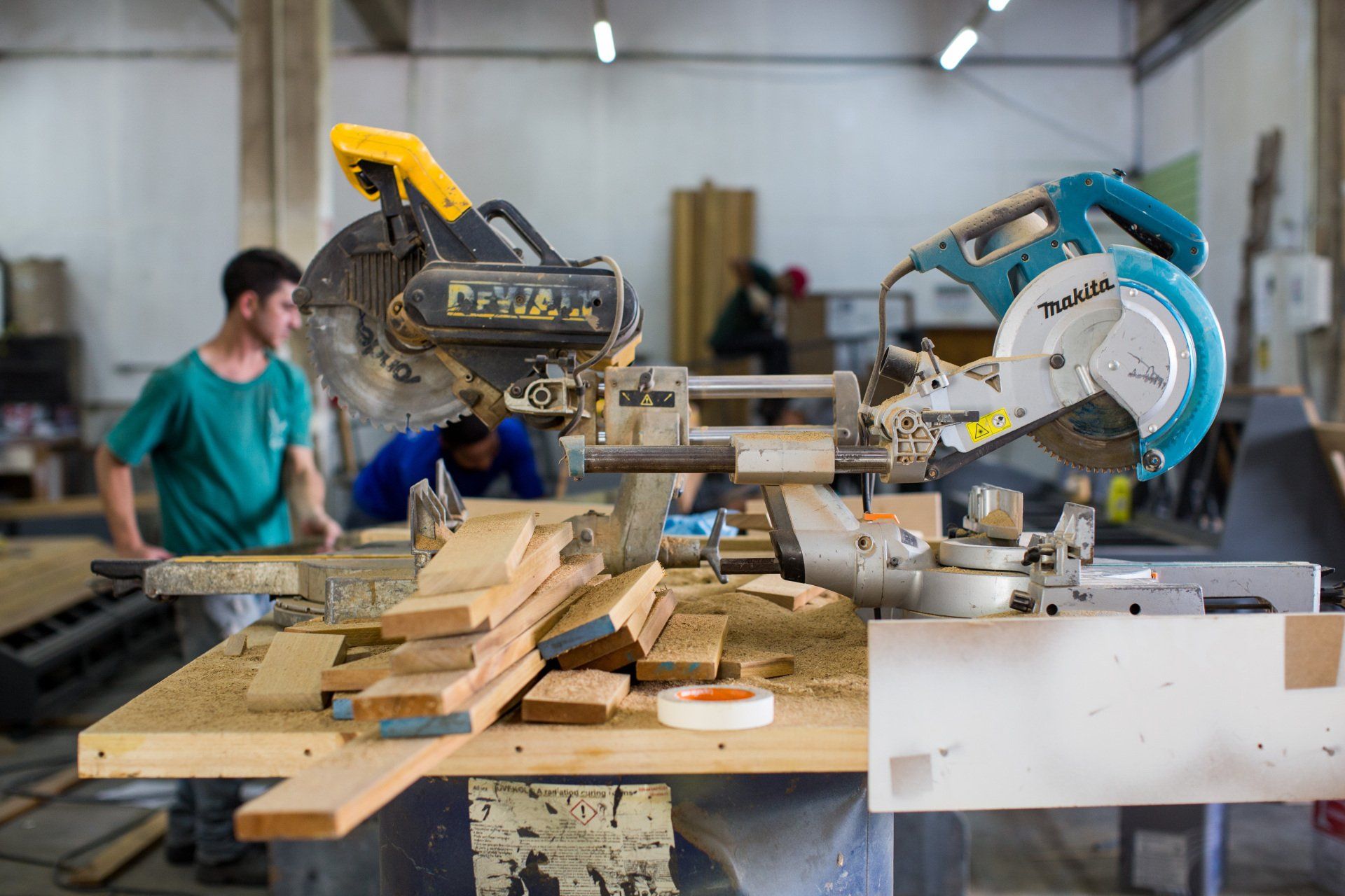 Um homem está usando uma serra circular para cortar madeira em uma oficina.