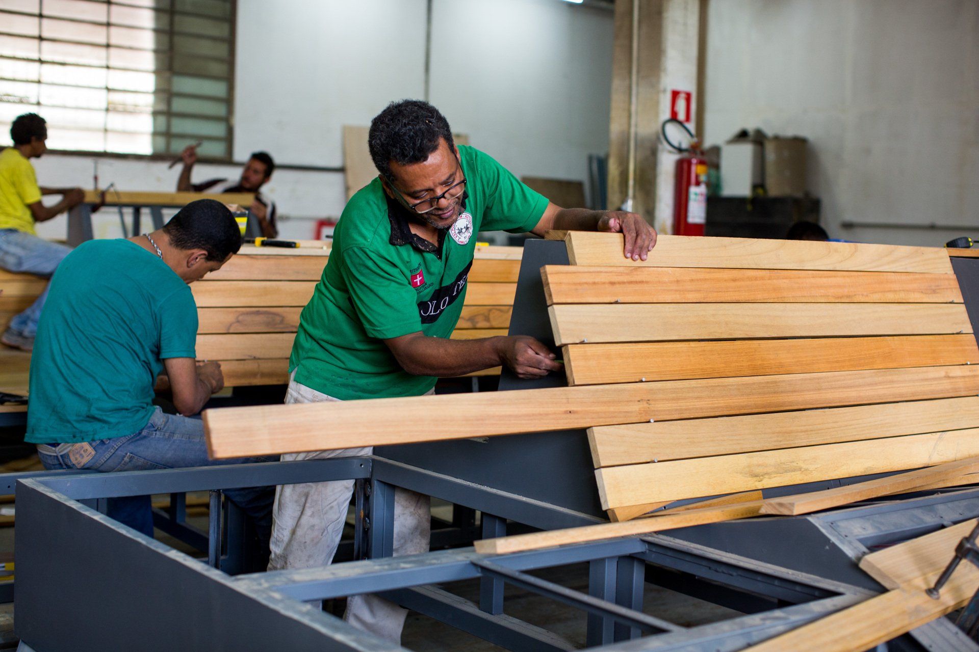 Dois homens estão trabalhando em um pedaço de madeira em uma fábrica.