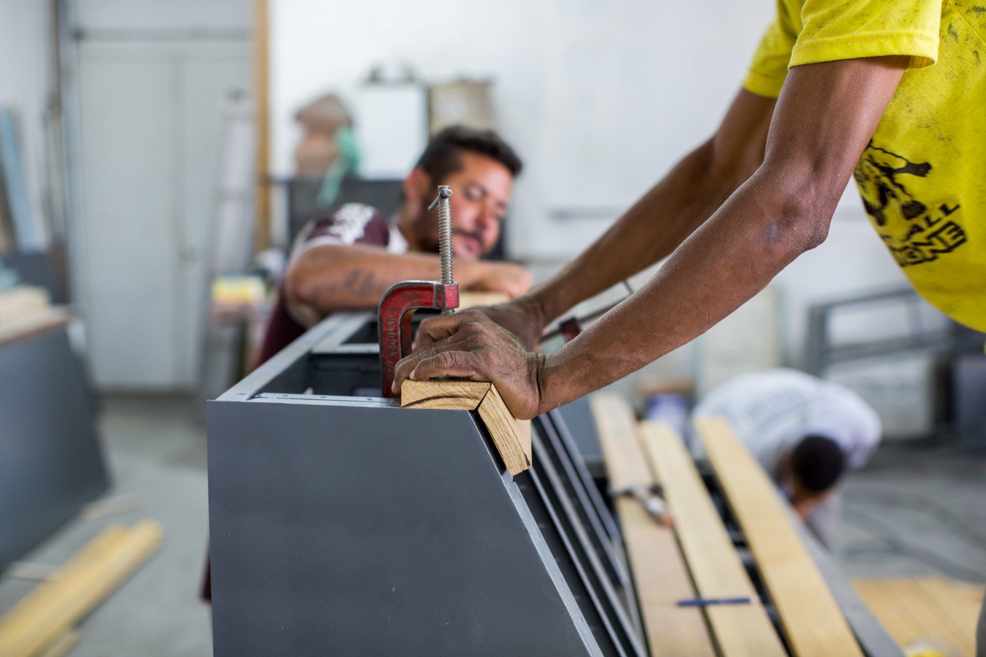 Dois homens estão trabalhando em um pedaço de madeira em uma oficina.
