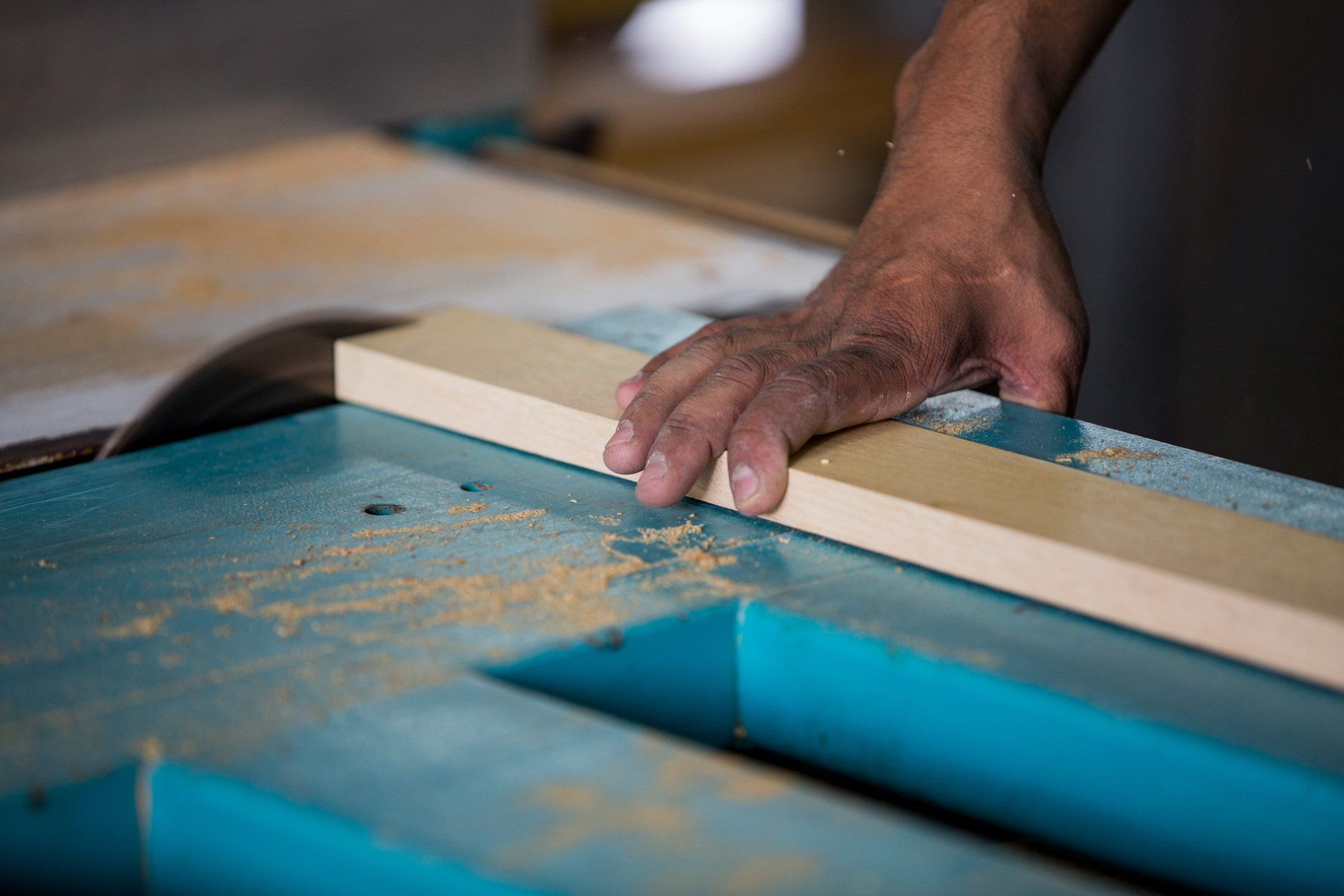 Uma pessoa está cortando um pedaço de madeira em uma serra de mesa.