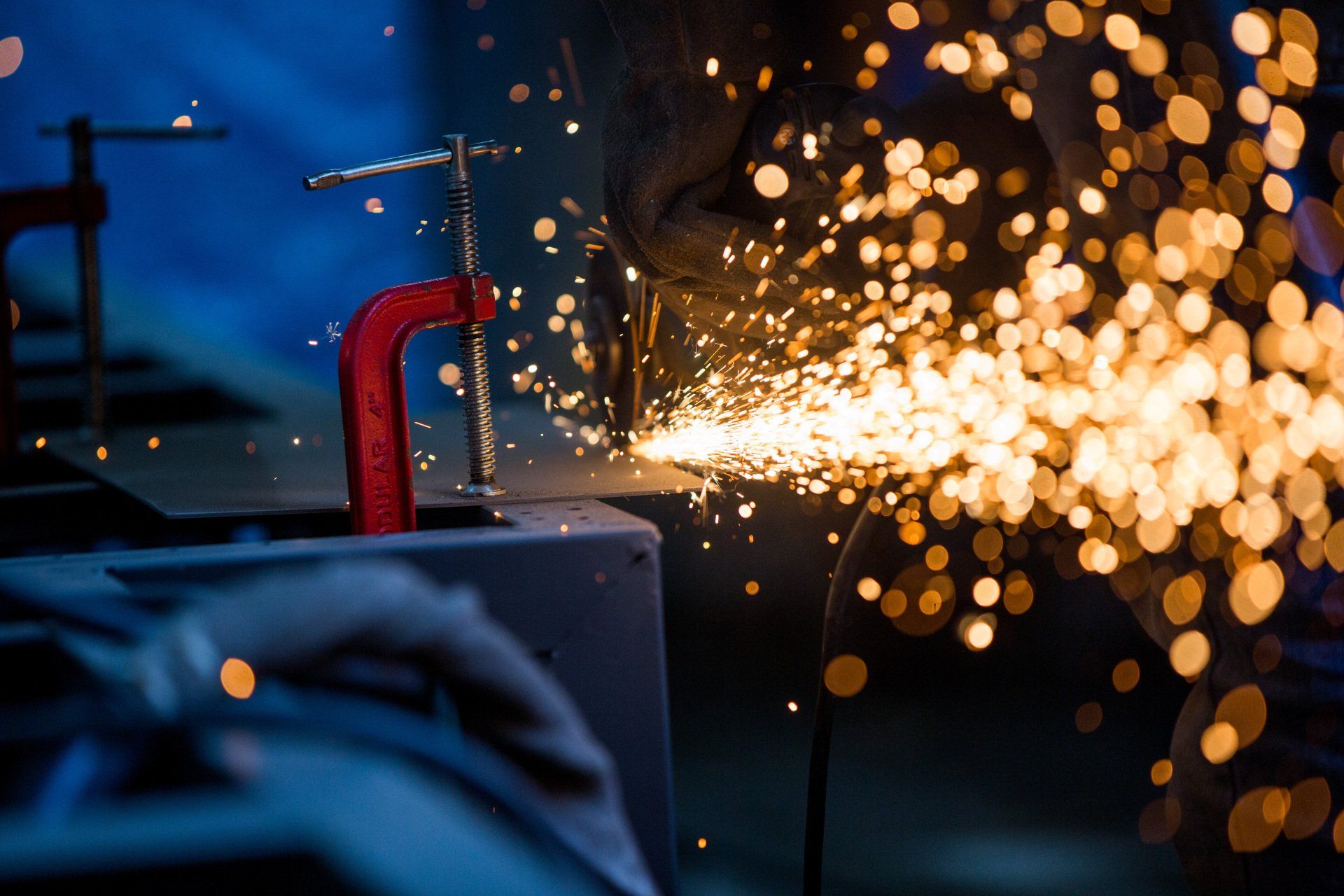 Uma pessoa está moendo um pedaço de metal com um moedor.