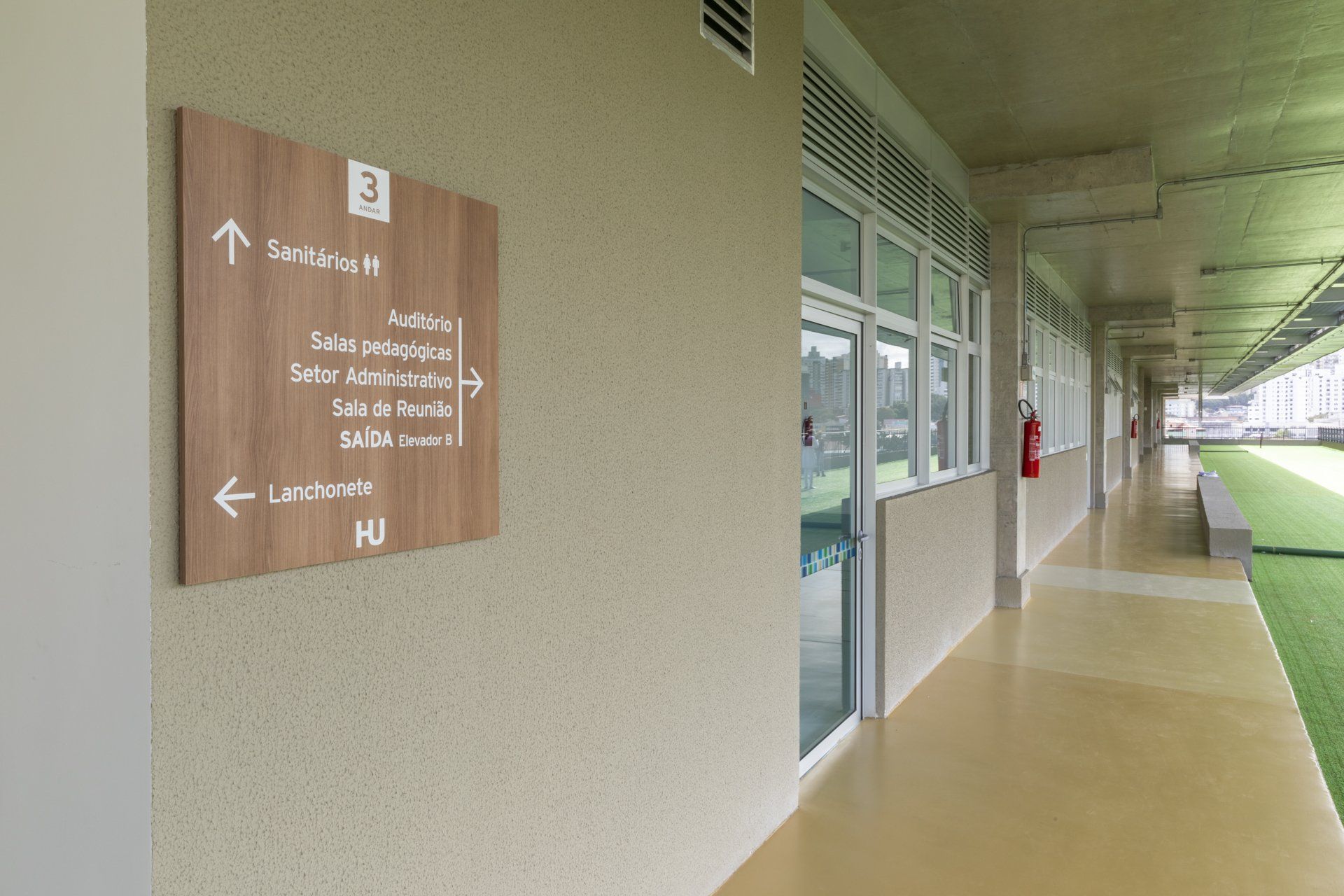 Um longo corredor com uma placa de madeira na parede.