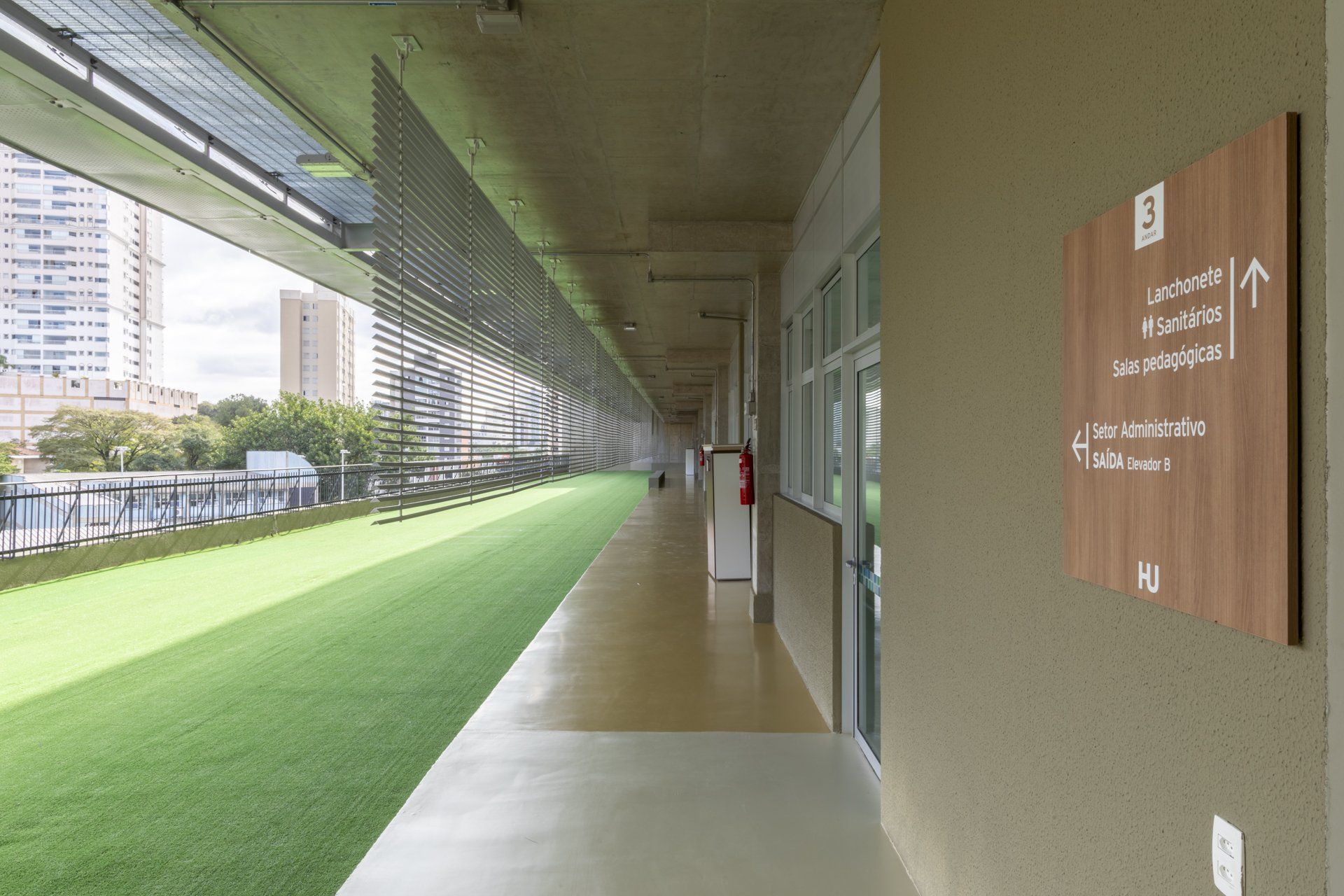 Um longo corredor com grama ao lado e uma placa na parede.