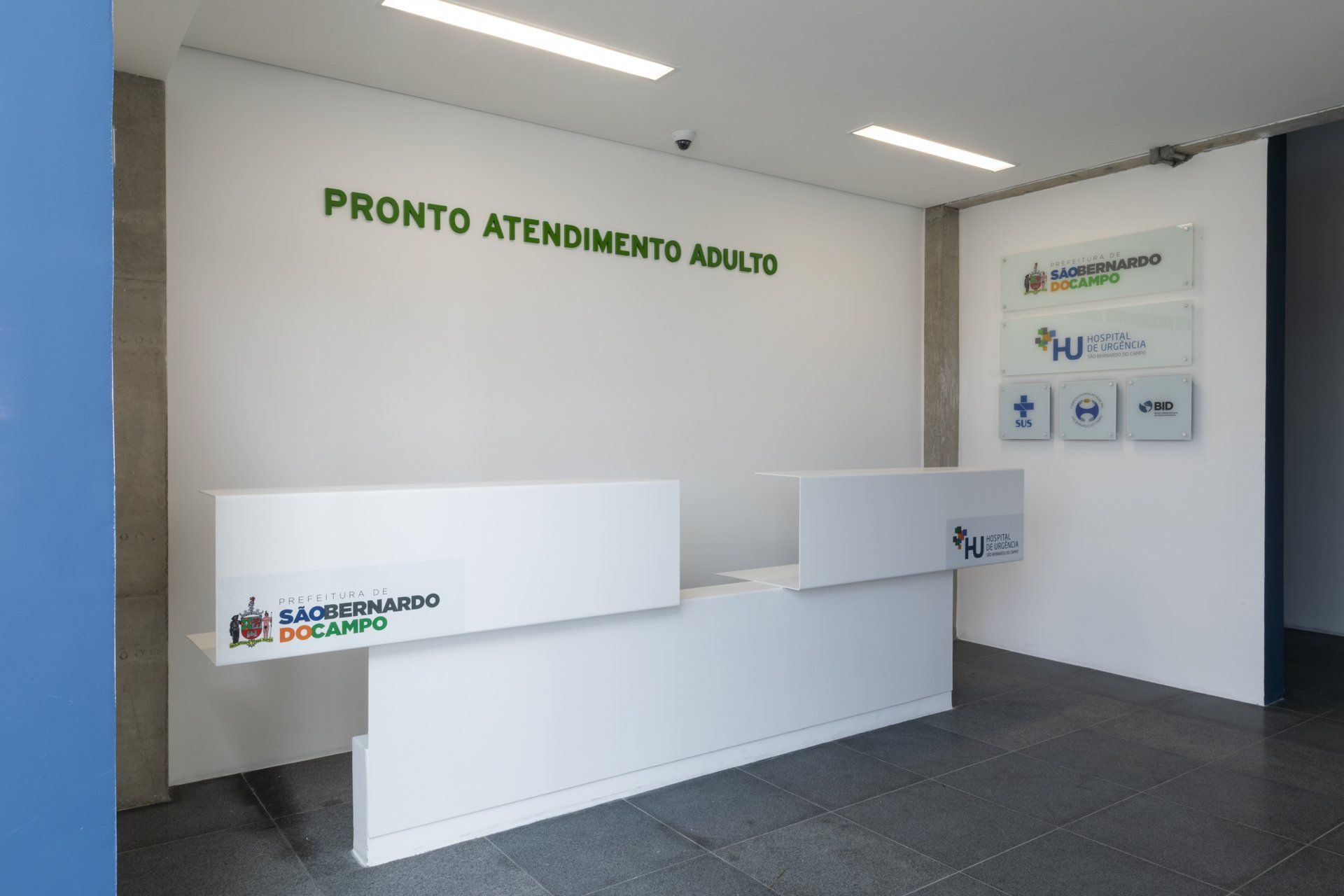 Uma recepção branca em frente a uma parede que diz pronto atendimento adulto