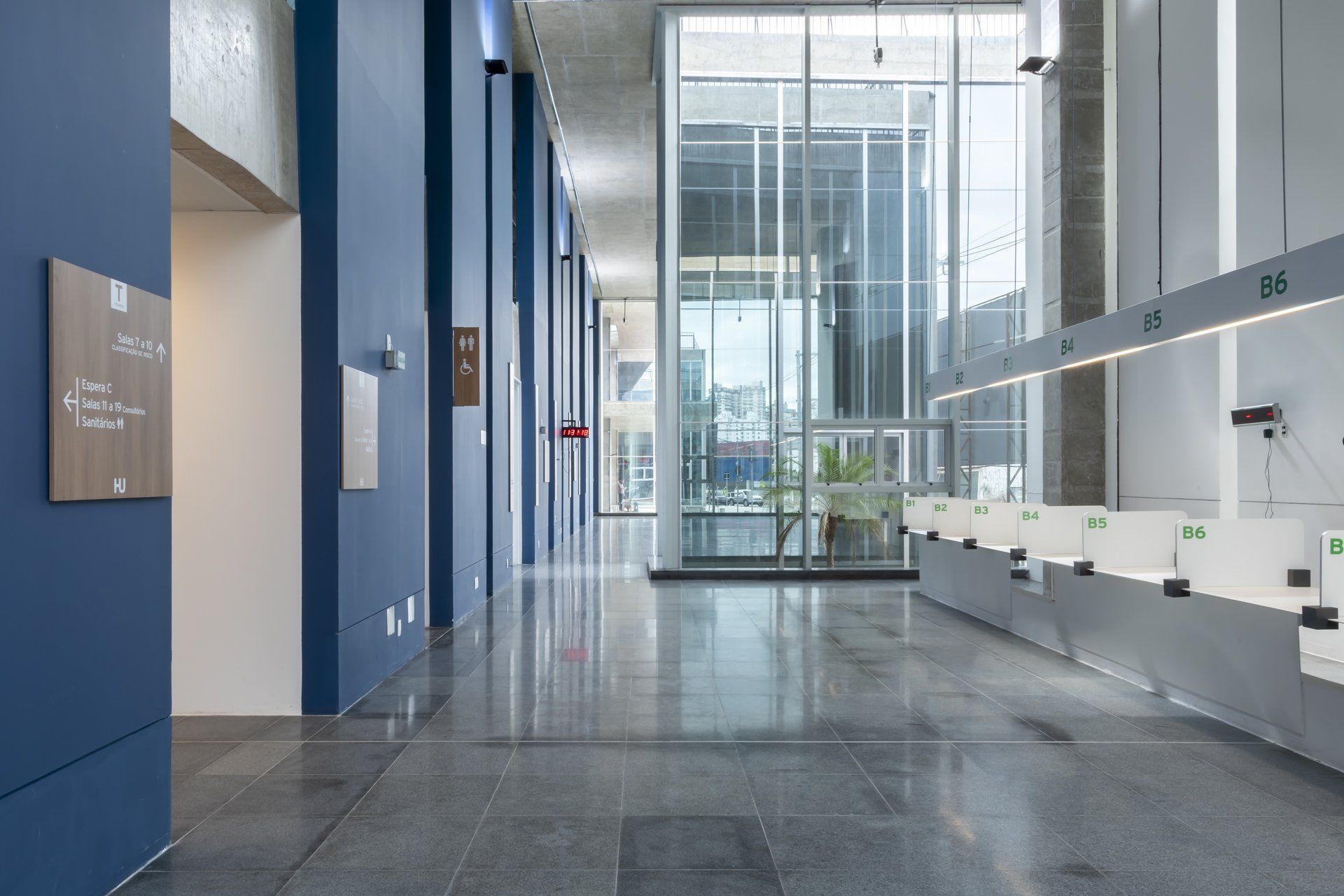 Um longo corredor em um prédio com muitas janelas e mesas.