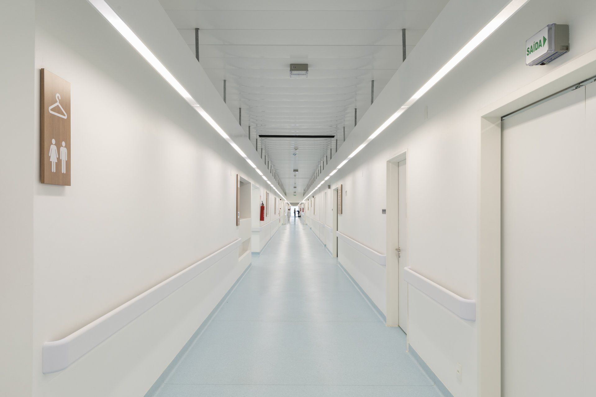 Um corredor de hospital vazio com piso azul e paredes brancas.