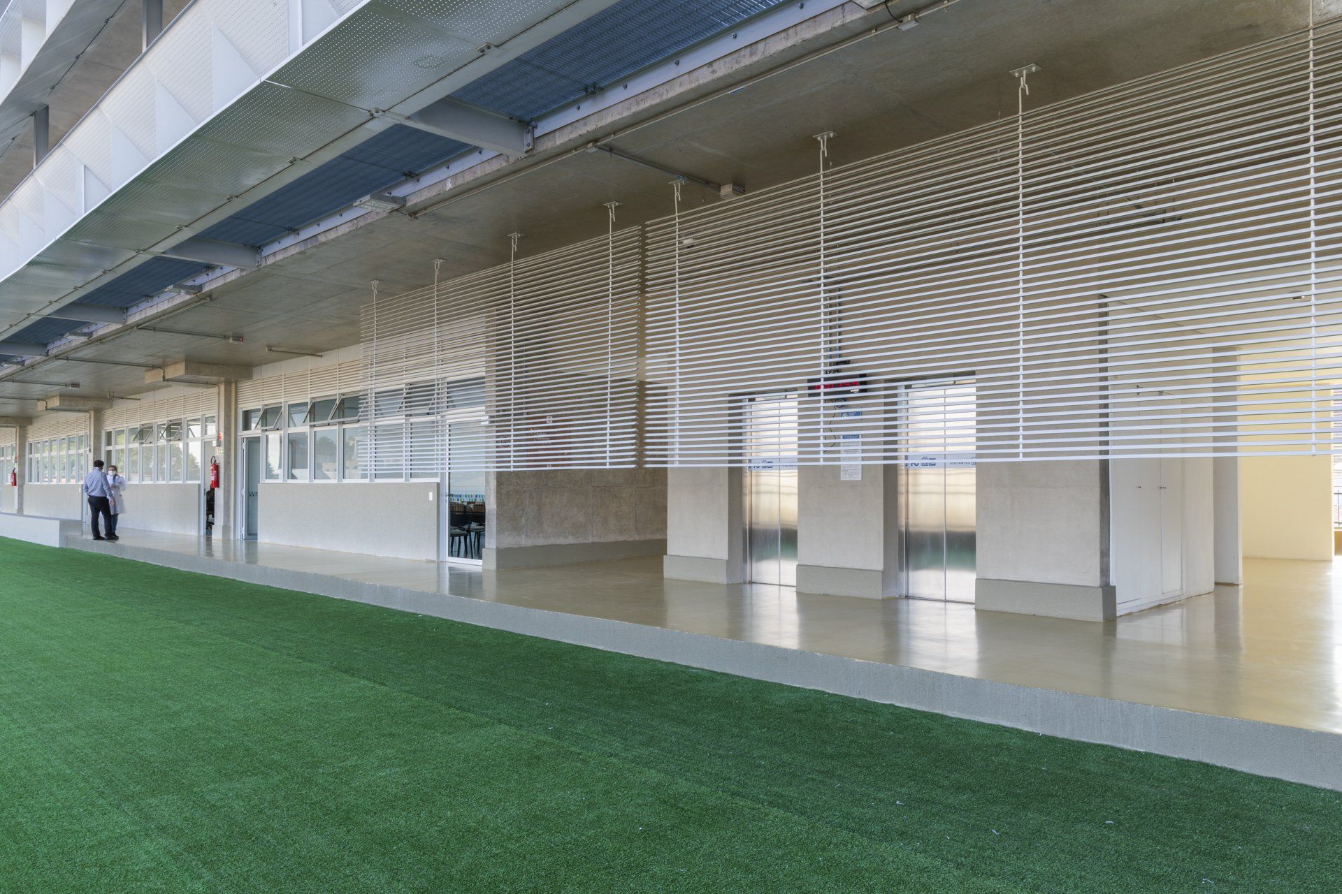 Um prédio grande com muitas janelas e uma área gramada na frente.