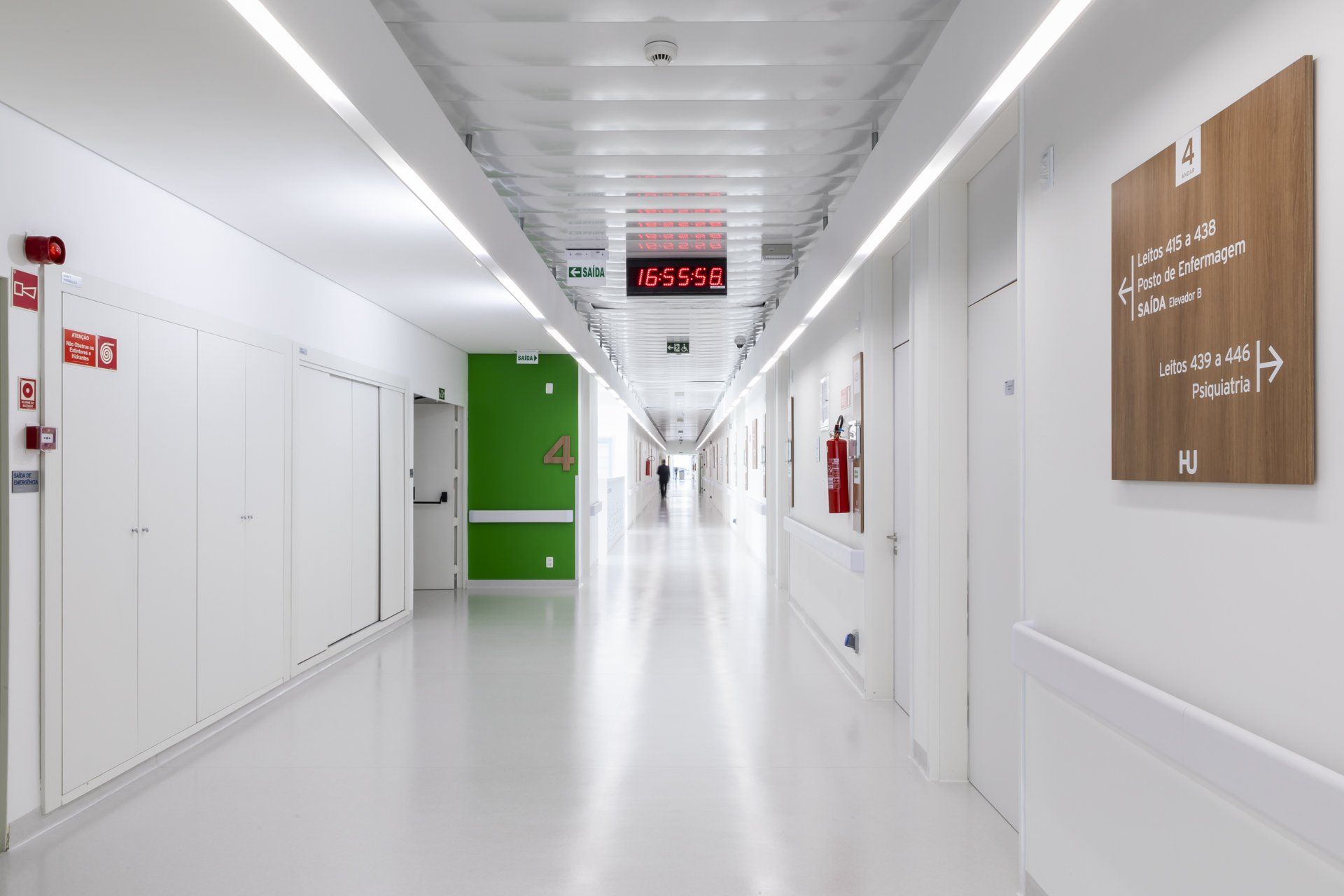 Um longo corredor de um hospital com um extintor de incêndio na parede.