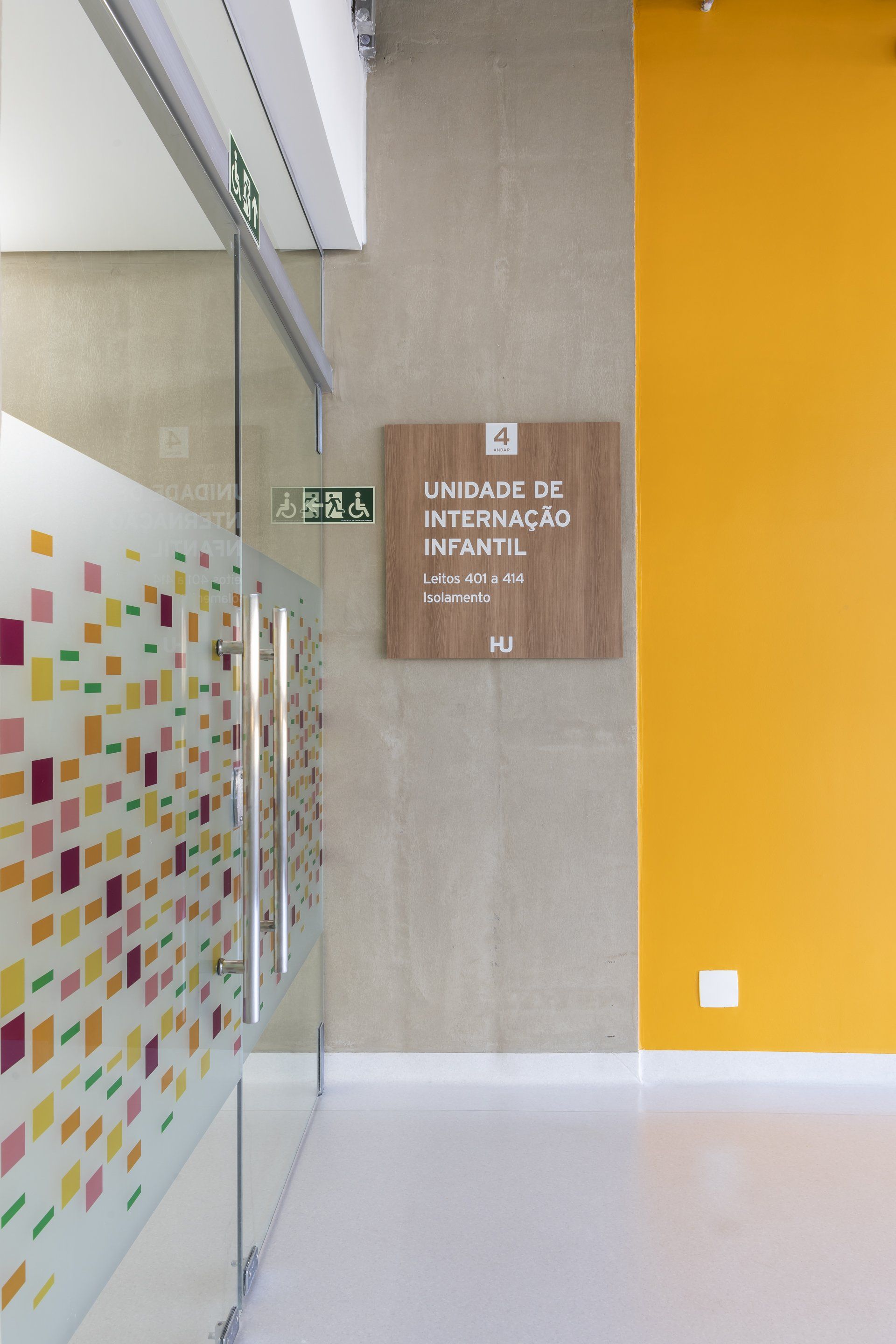 Um corredor com uma placa de madeira na parede e uma parede amarela.
