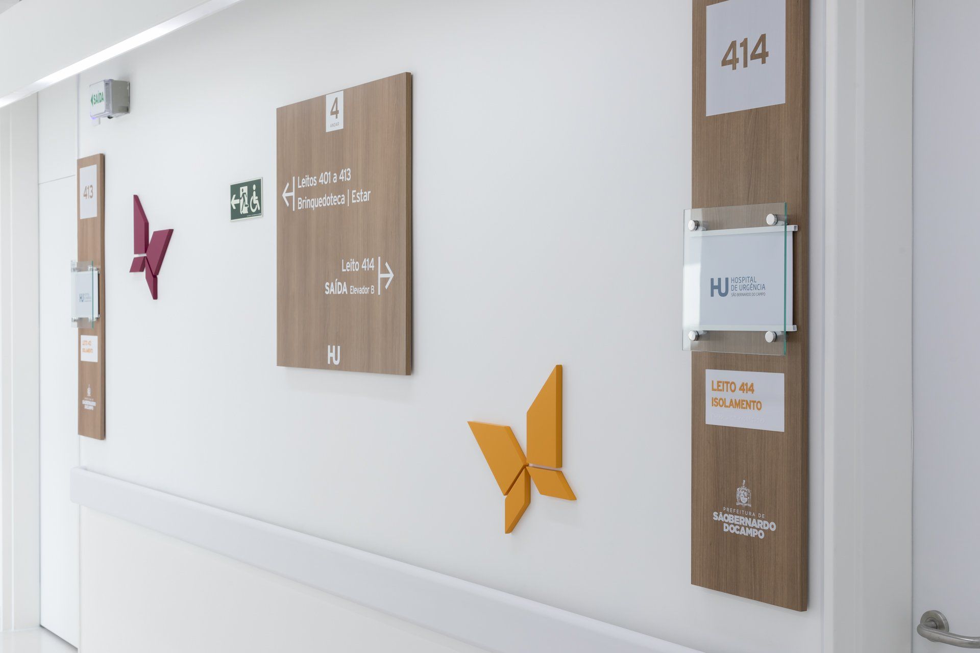 Um corredor de hospital com placas na parede e uma borboleta na parede.