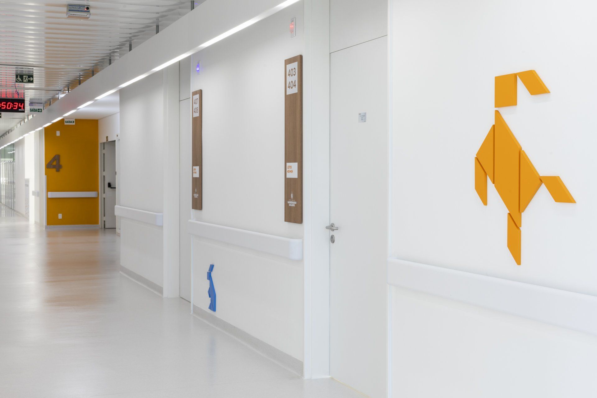 Um corredor de hospital com um cachorro de origami amarelo na parede.