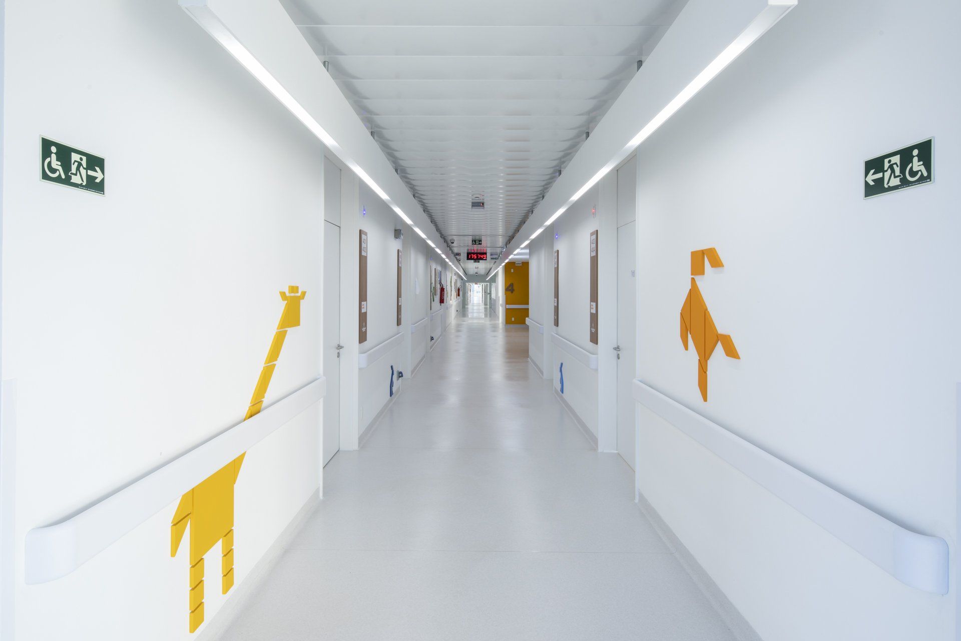 Um corredor de hospital com uma girafa e um macaco pintados na parede