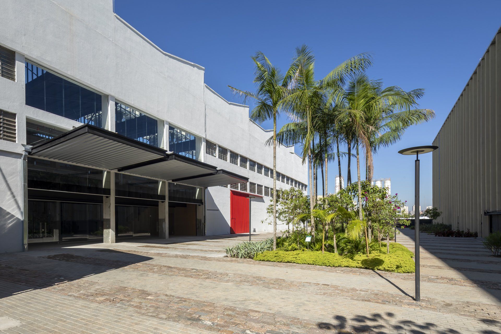 Um grande edifício branco com uma porta vermelha e palmeiras na frente.
