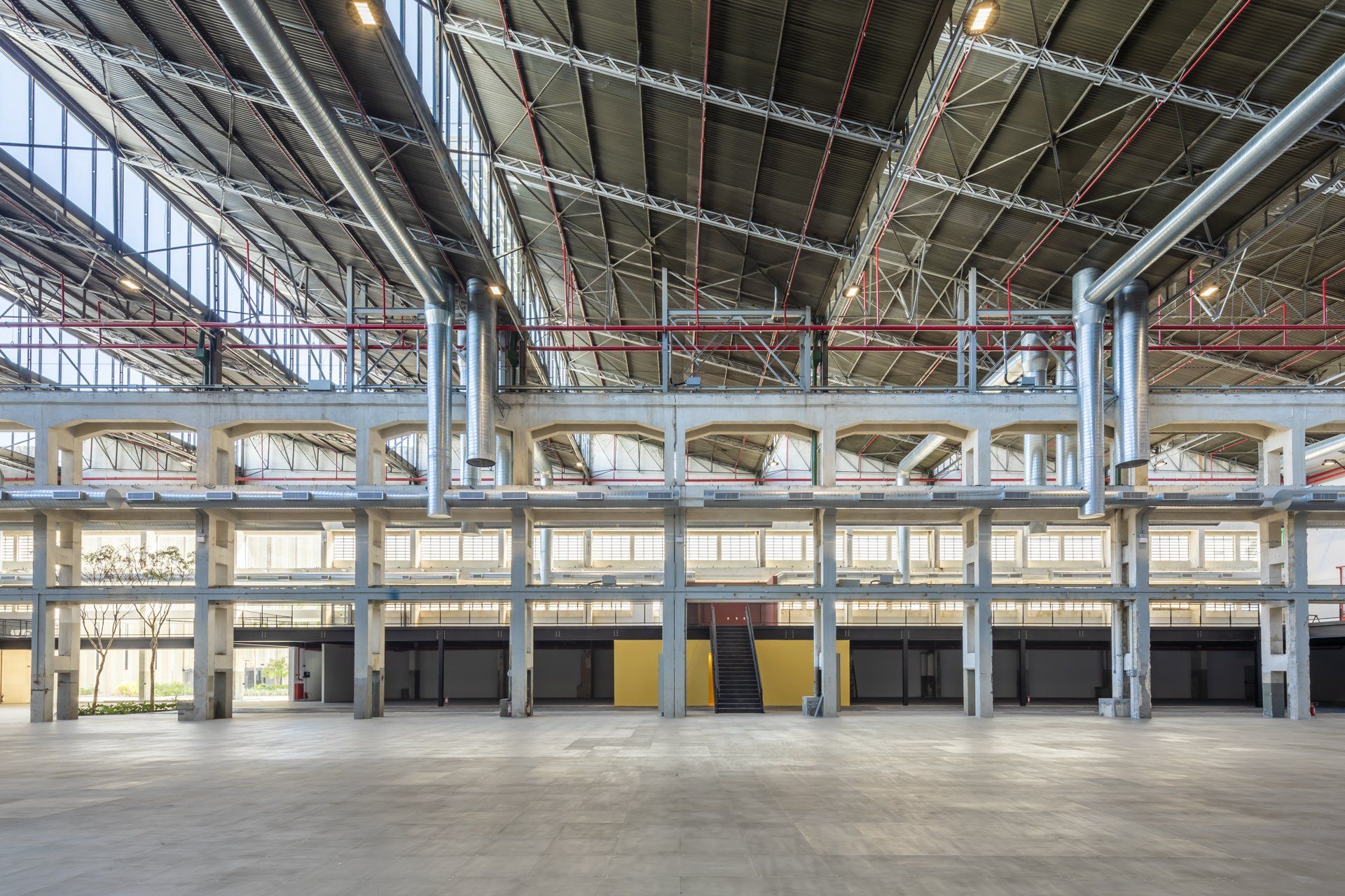Um grande armazém vazio com muitas janelas e canos saindo do teto.