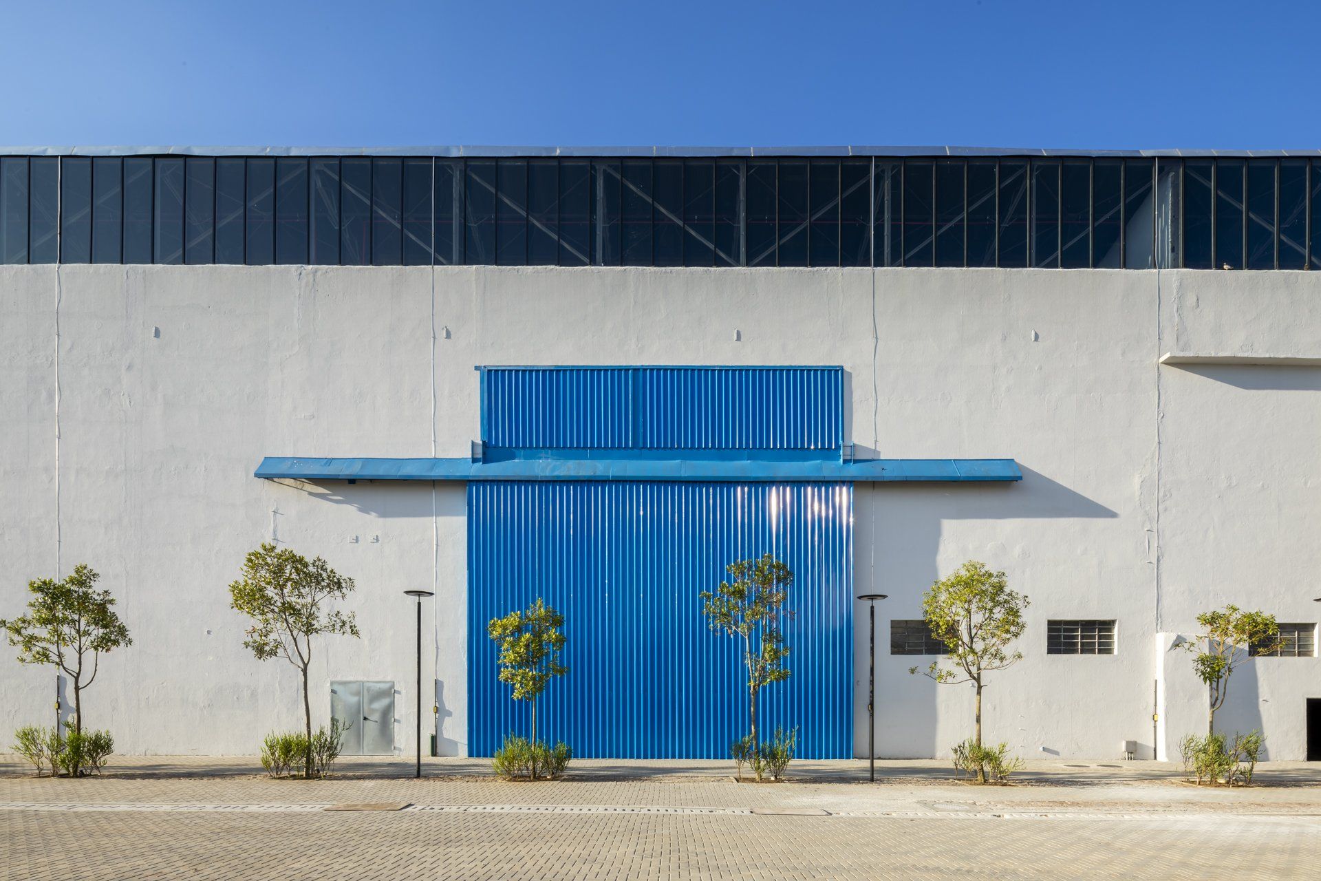 Um prédio branco com uma porta azul e árvores na frente