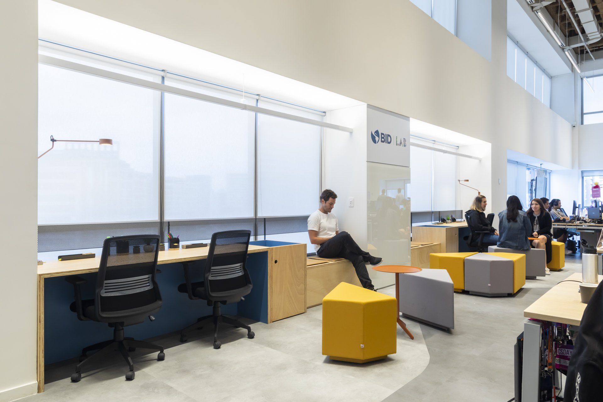 Um grupo de pessoas está sentado em mesas de um escritório.