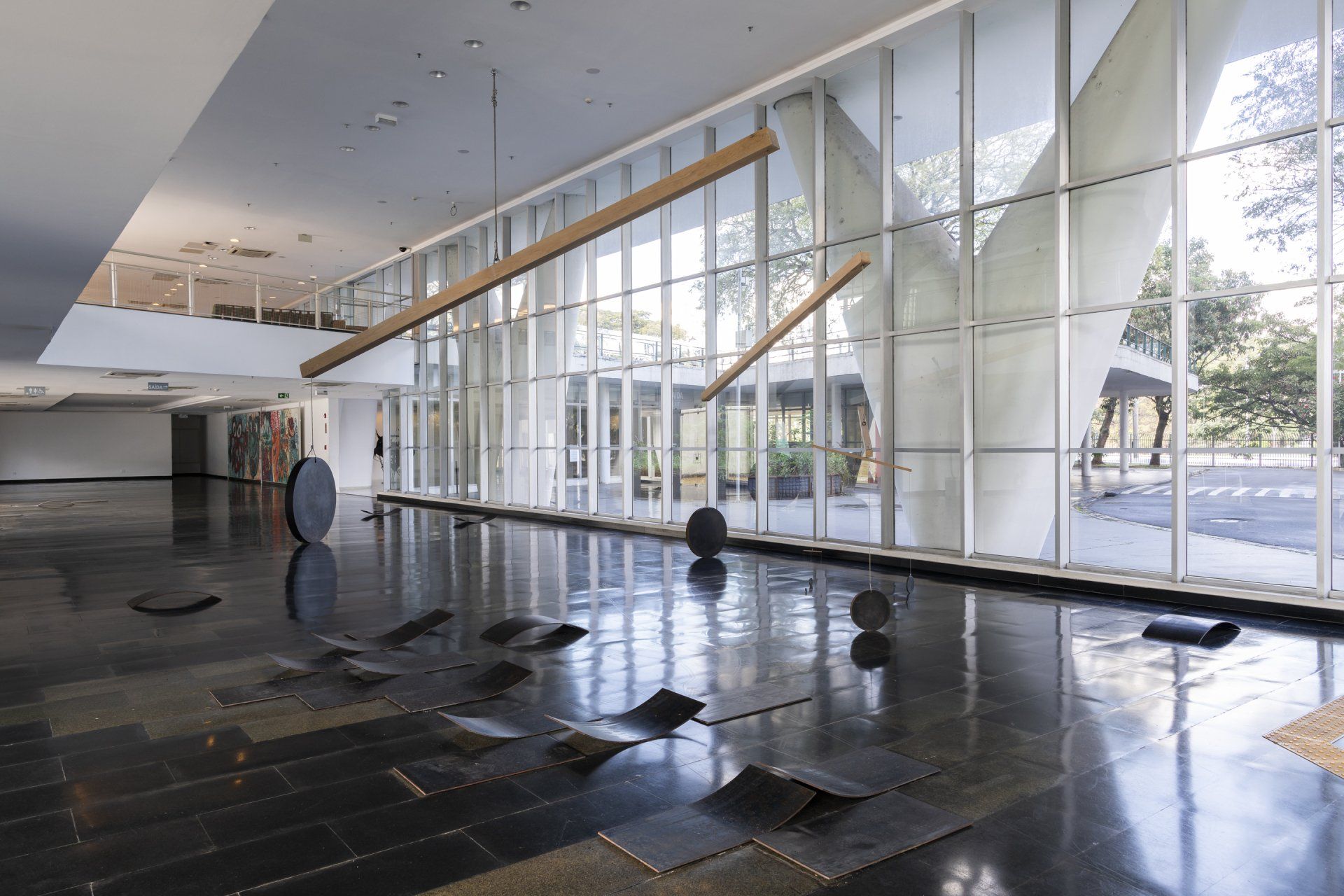 Uma grande sala vazia com muitas janelas e esculturas no chão.