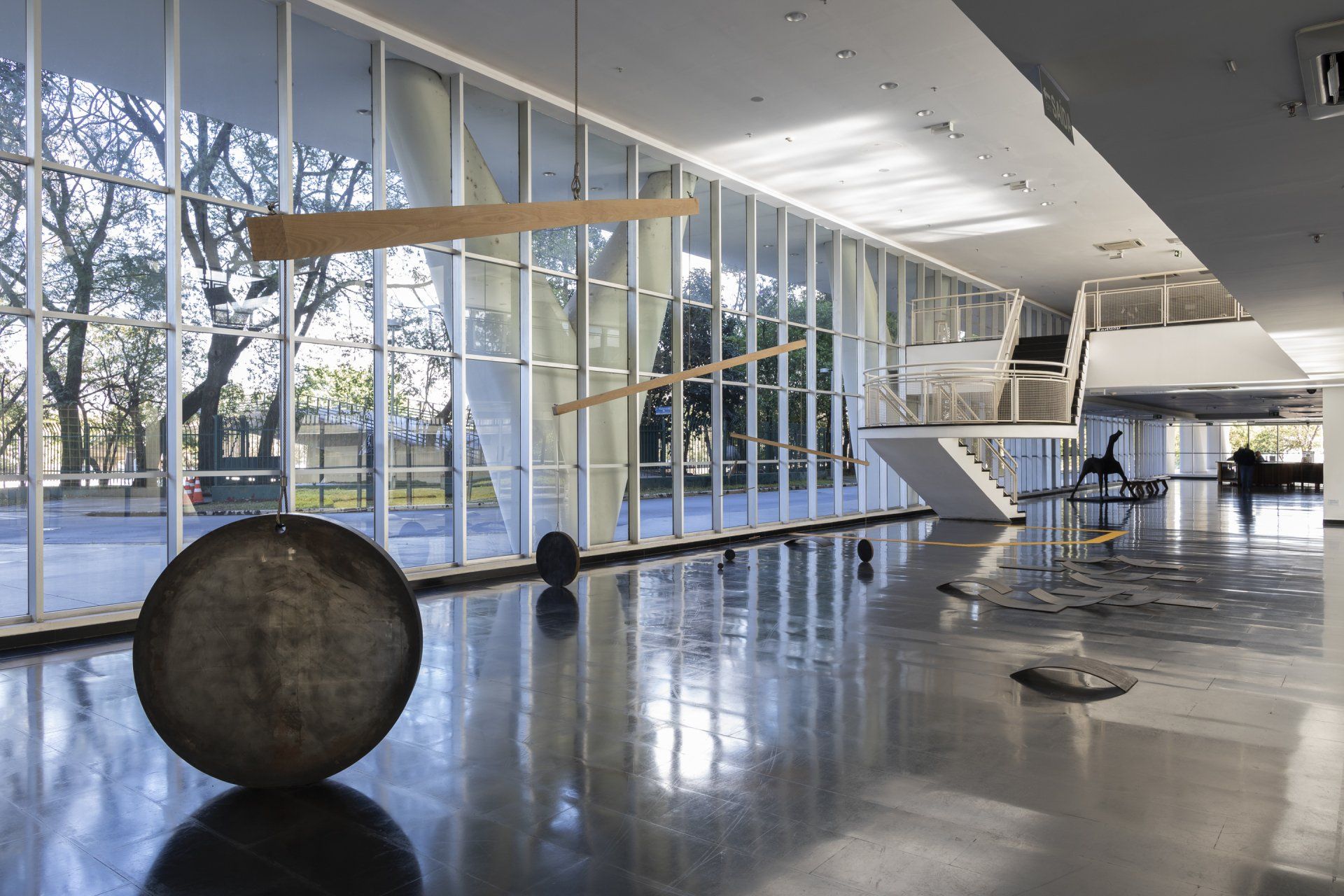 Uma grande sala com muitas janelas e uma escultura no chão.