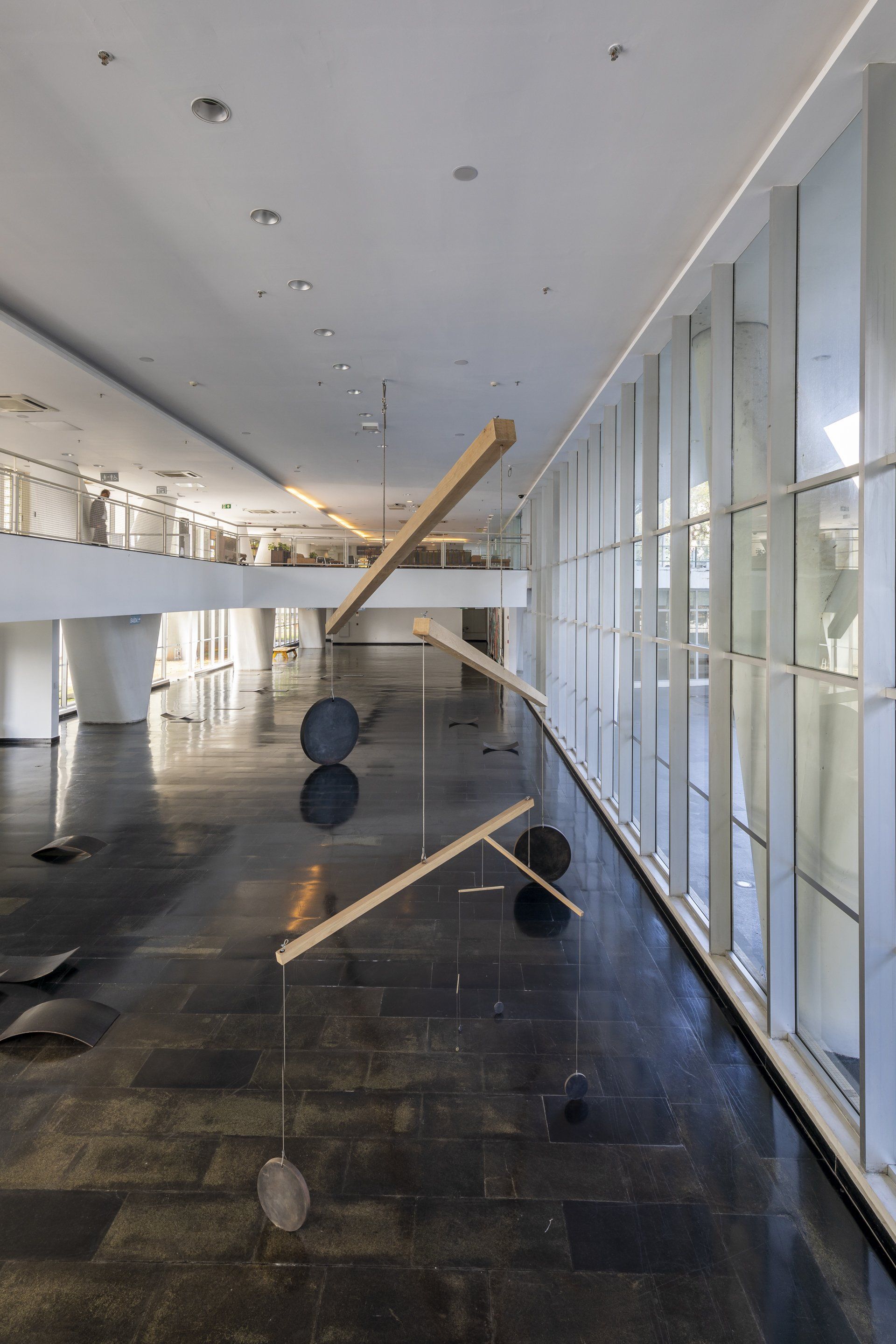 Uma grande sala com muitas janelas e uma escultura no chão.